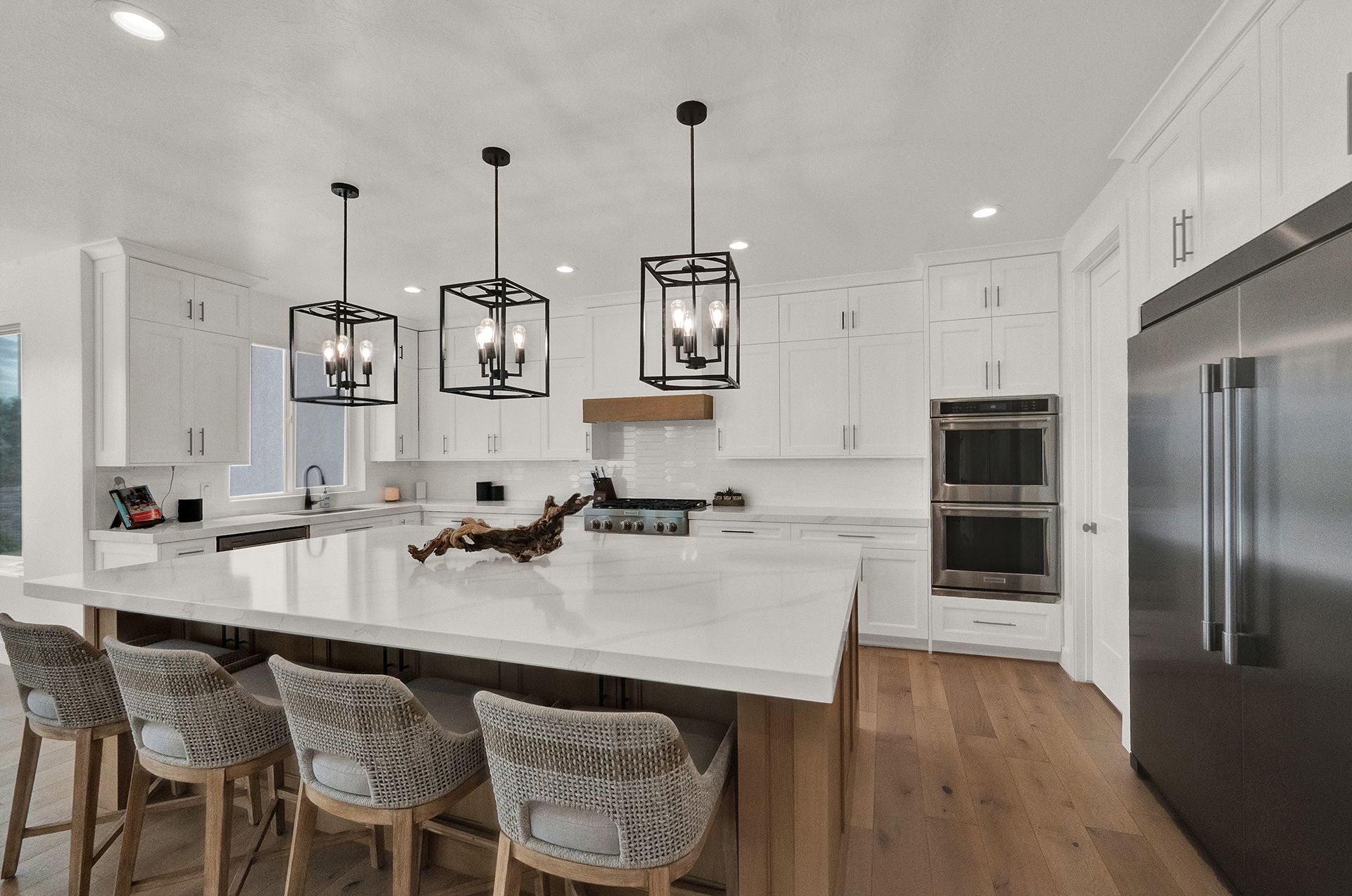 A kitchen with white cabinets , stainless steel appliances and a large island.