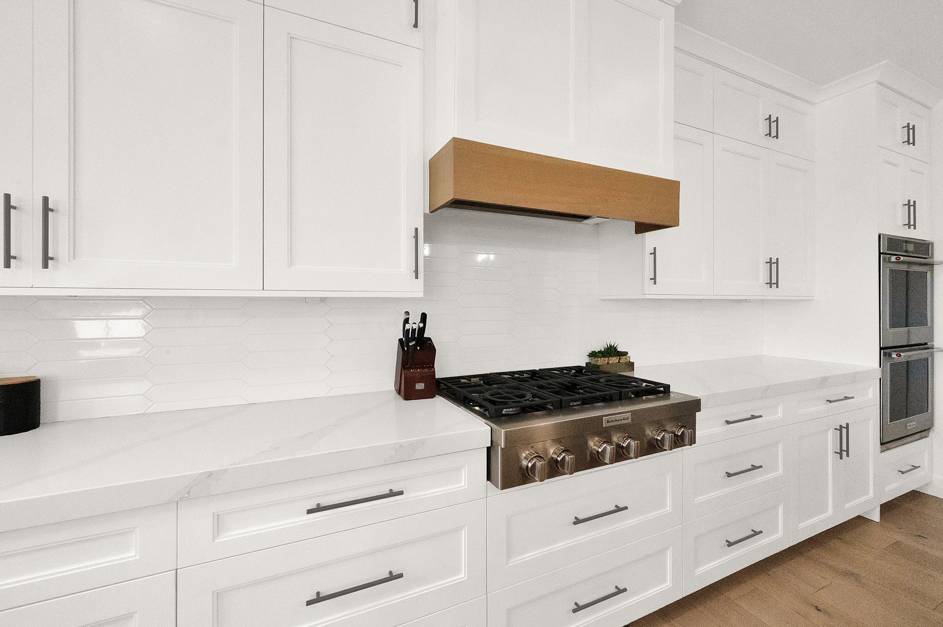 A kitchen with white cabinets and a stove top oven.