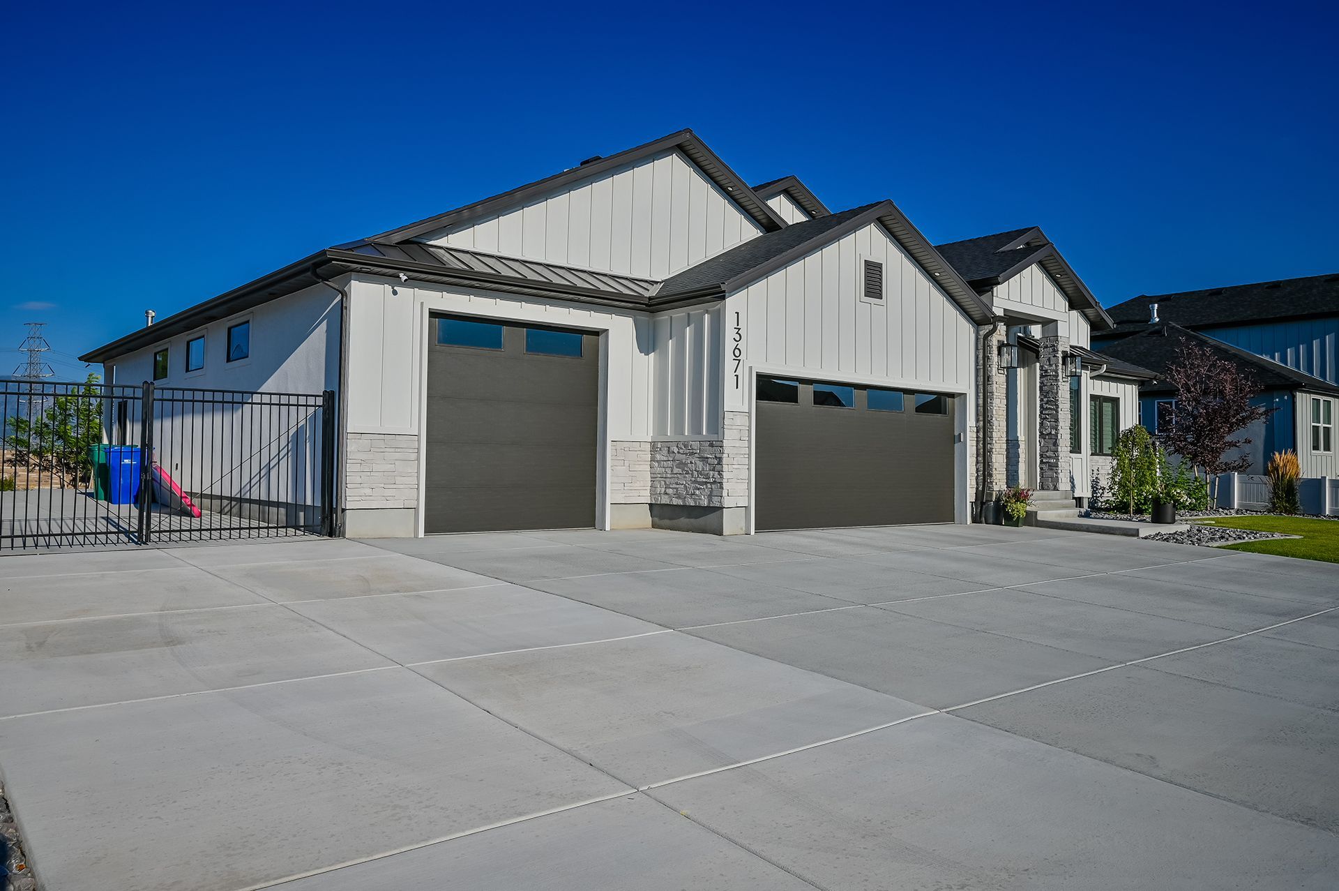 A large white house with two garage doors and a concrete driveway.