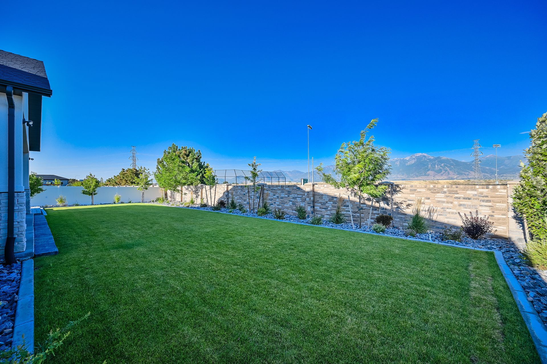 A large lush green lawn in front of a house with mountains in the background.