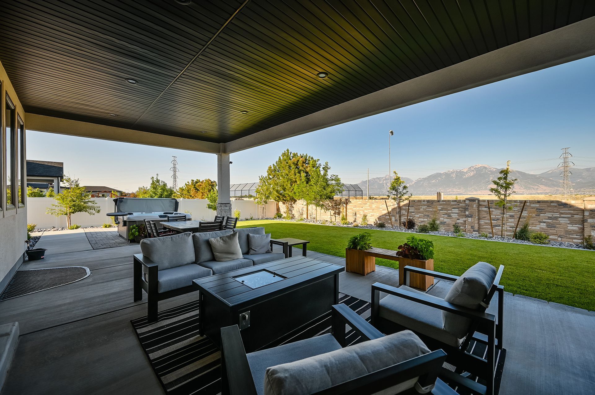 A patio with a couch , chairs , and a table with mountains in the background.