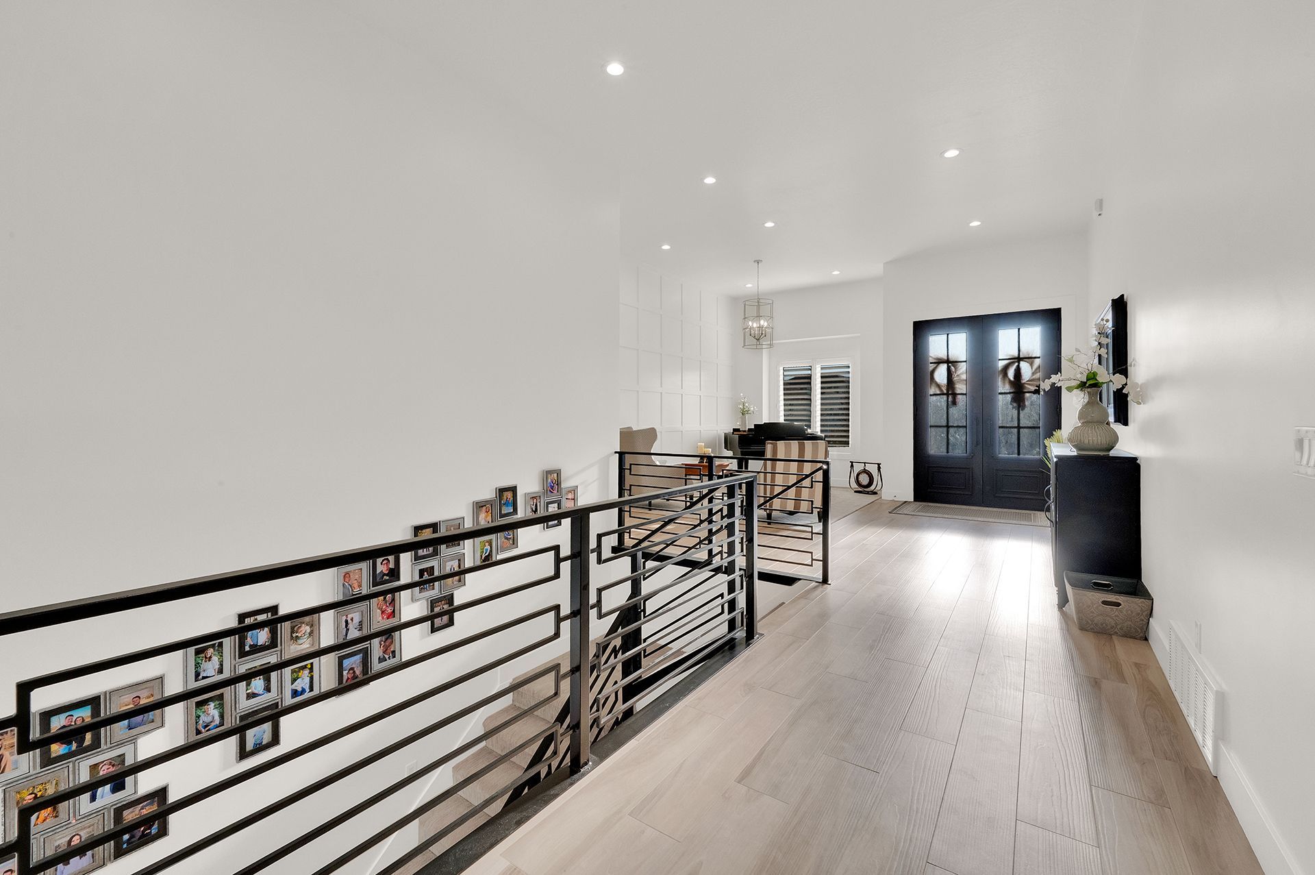 A hallway with a wrought iron railing leading to a living room.