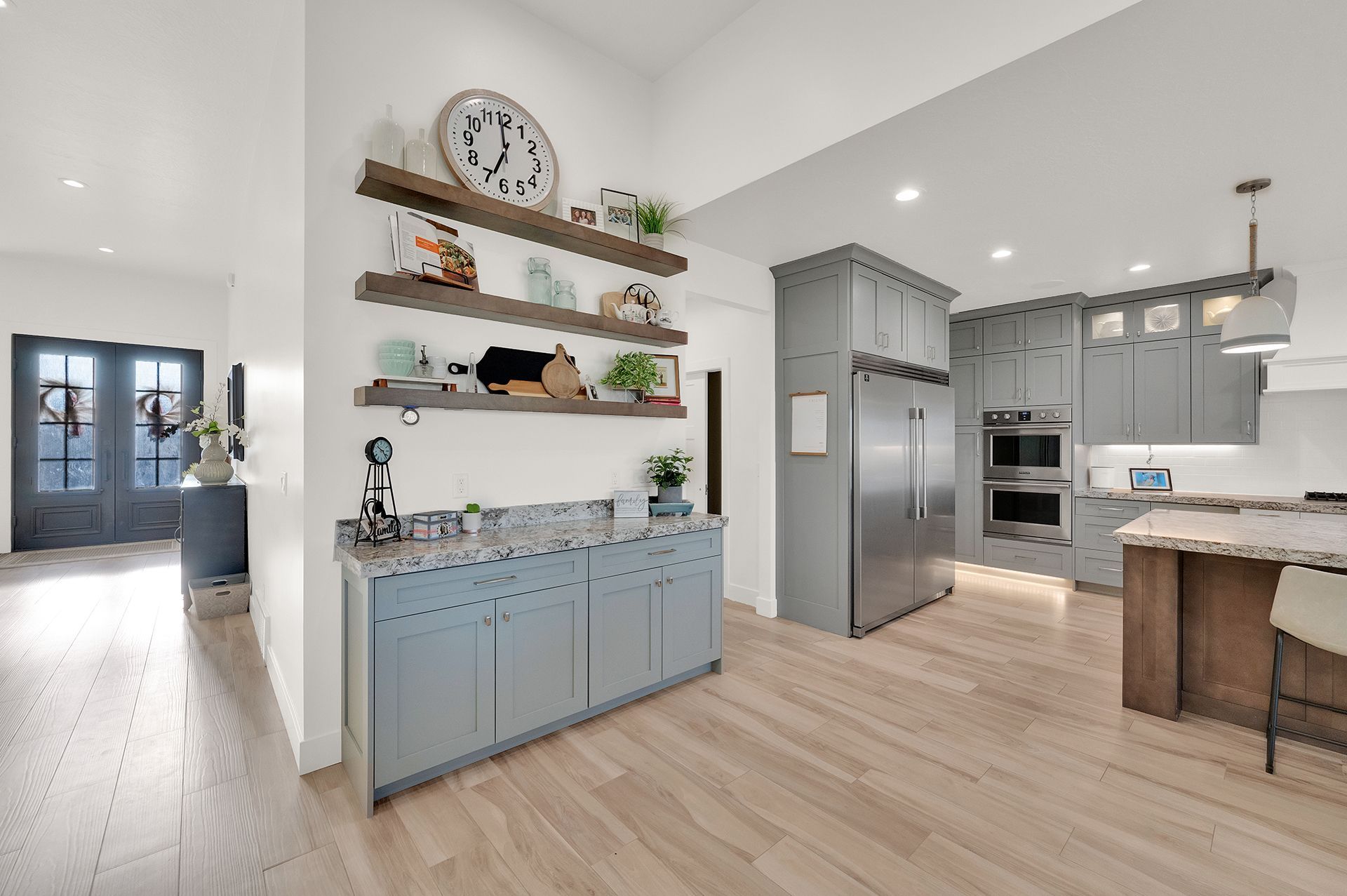A kitchen with gray cabinets , stainless steel appliances , and hardwood floors.