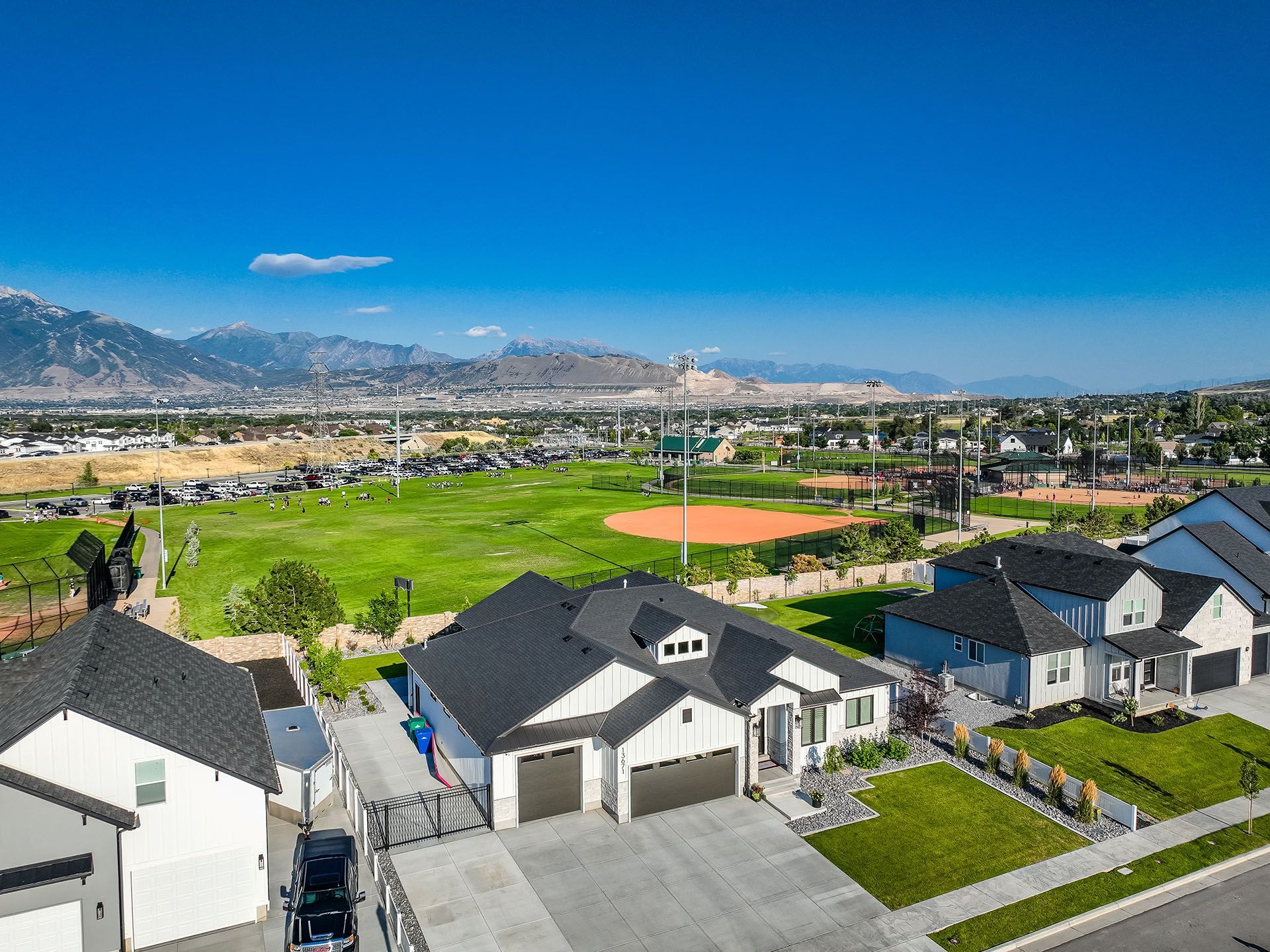 An aerial view of a residential neighborhood with a baseball field in the background.