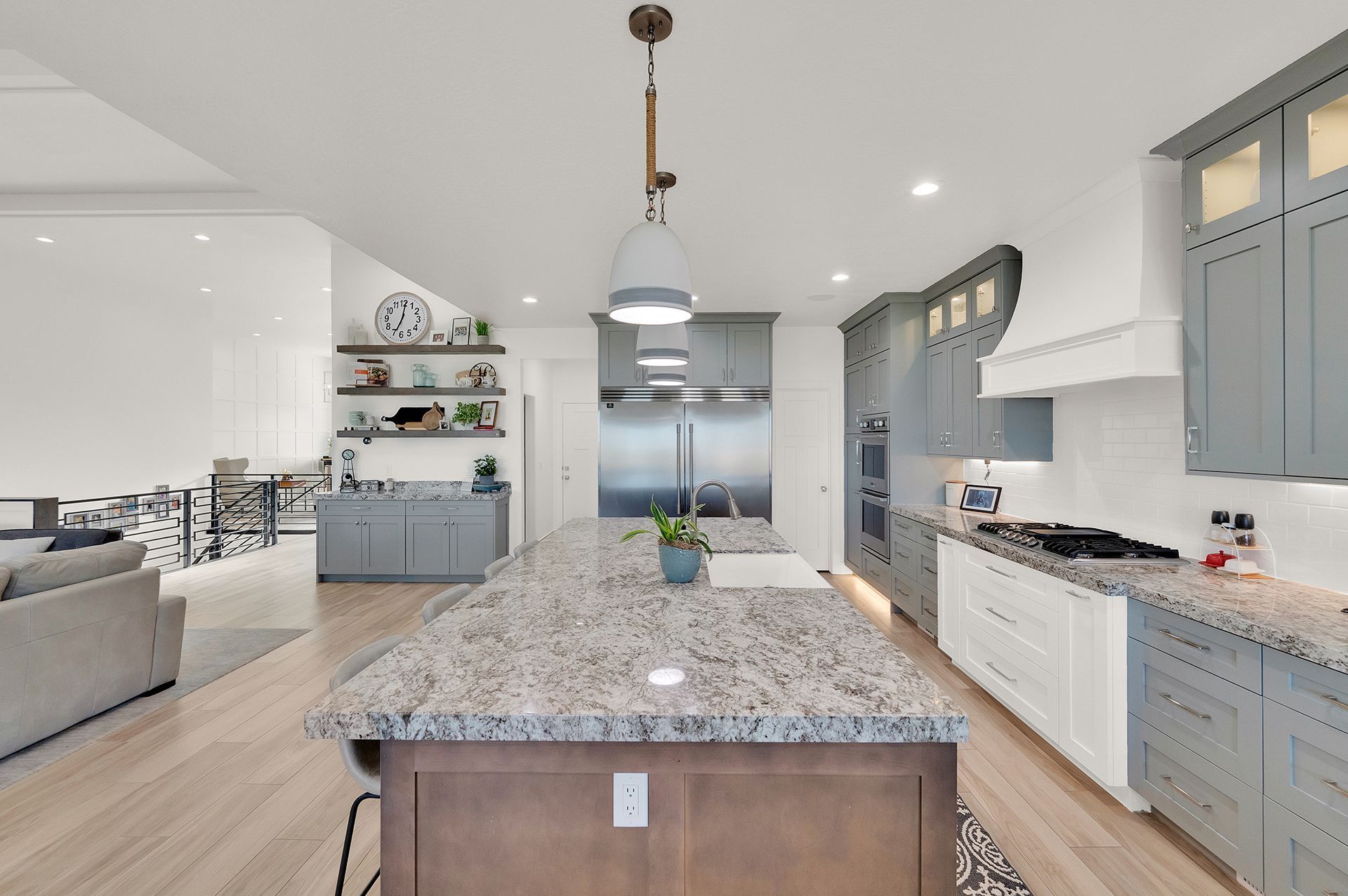 A kitchen with granite counter tops and gray cabinets