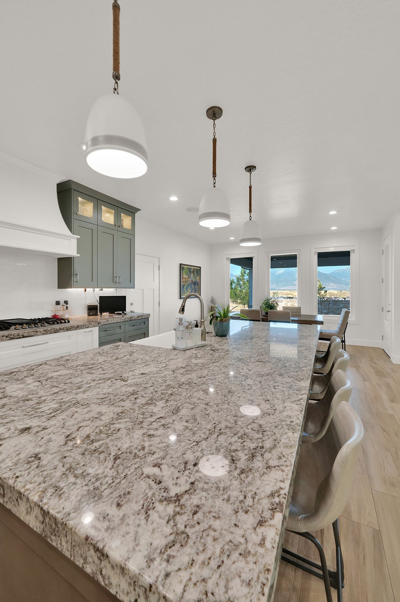 A kitchen with a large granite counter top and stools.