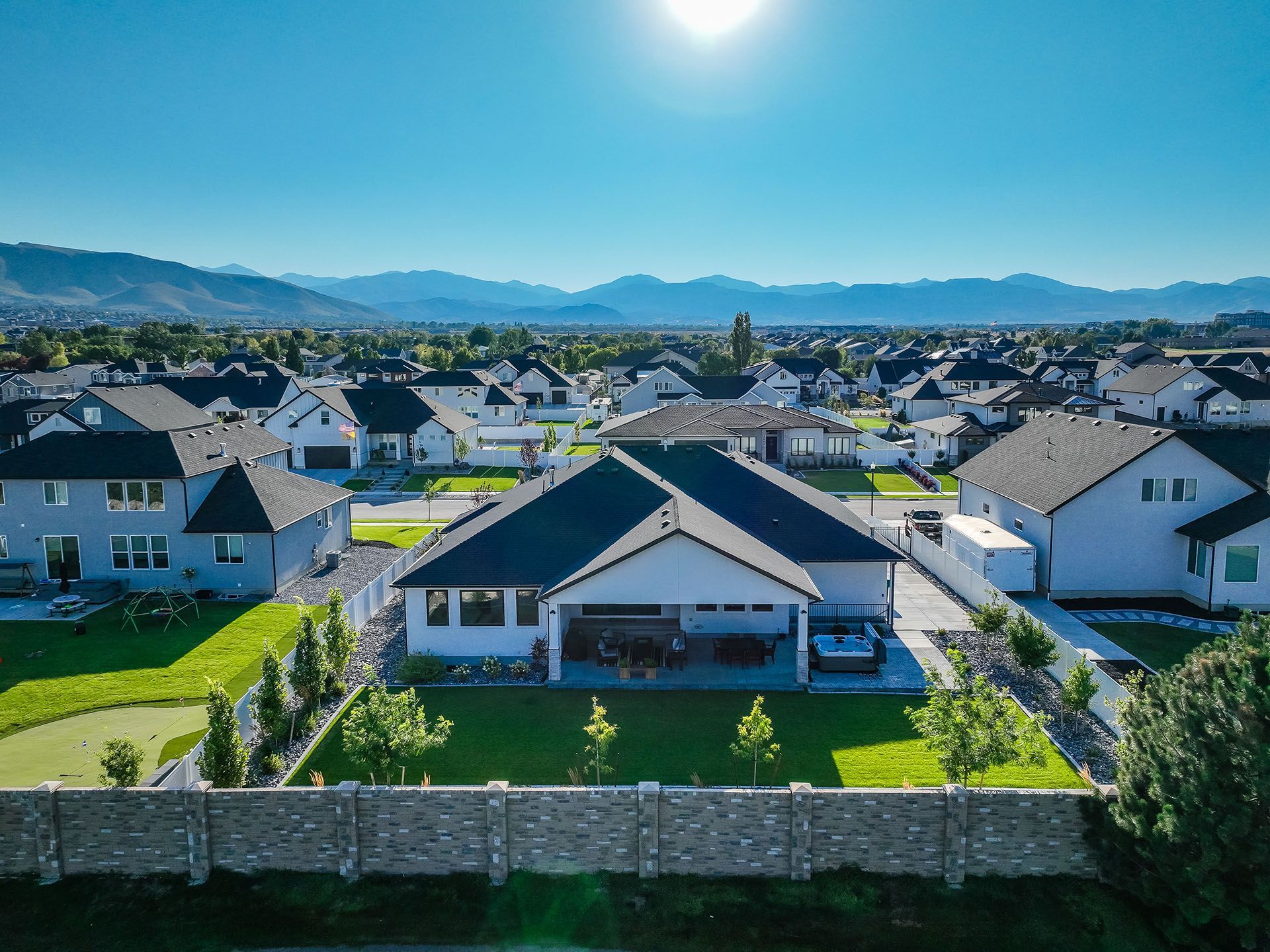 An aerial view of a house in a residential area with mountains in the background.