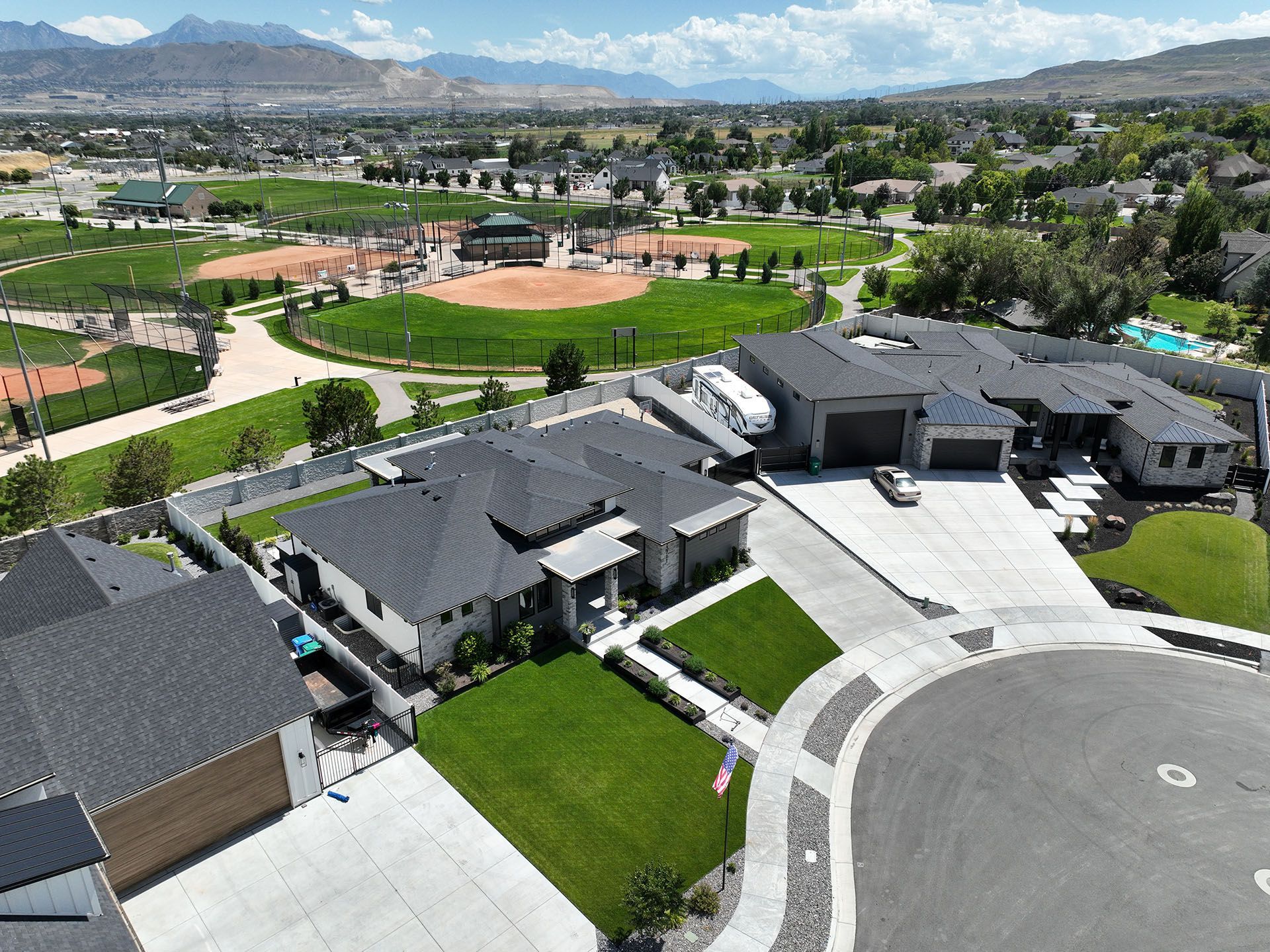 An aerial view of a residential neighborhood with a baseball field in the background.