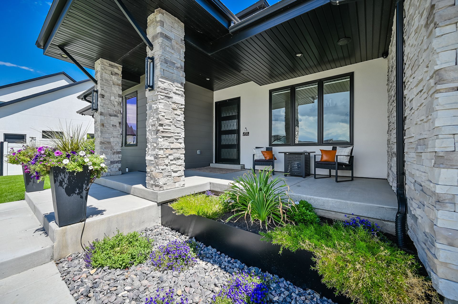 The front of a house with a porch and flowers in front of it.