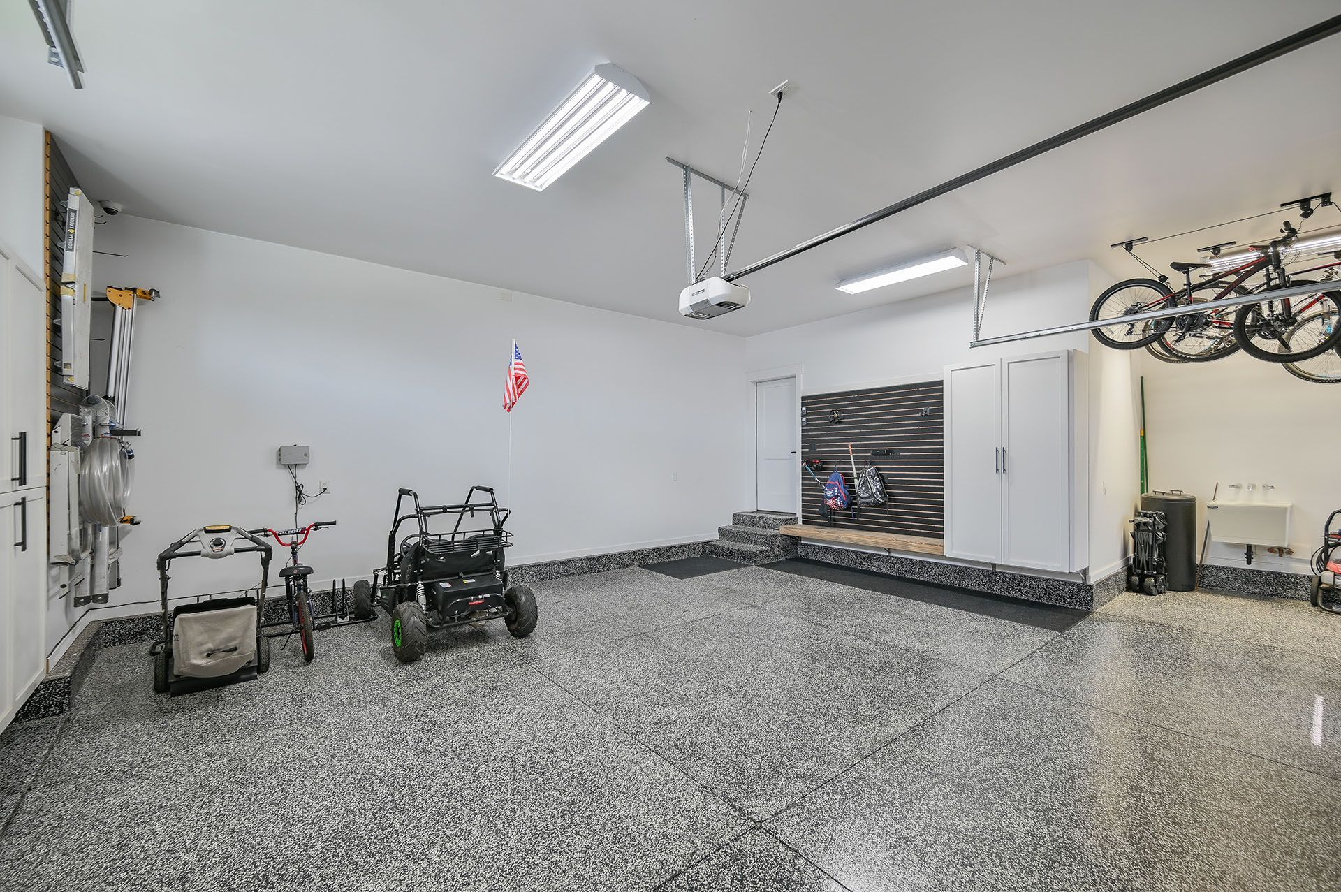A large garage with a lot of bikes hanging from the ceiling.
