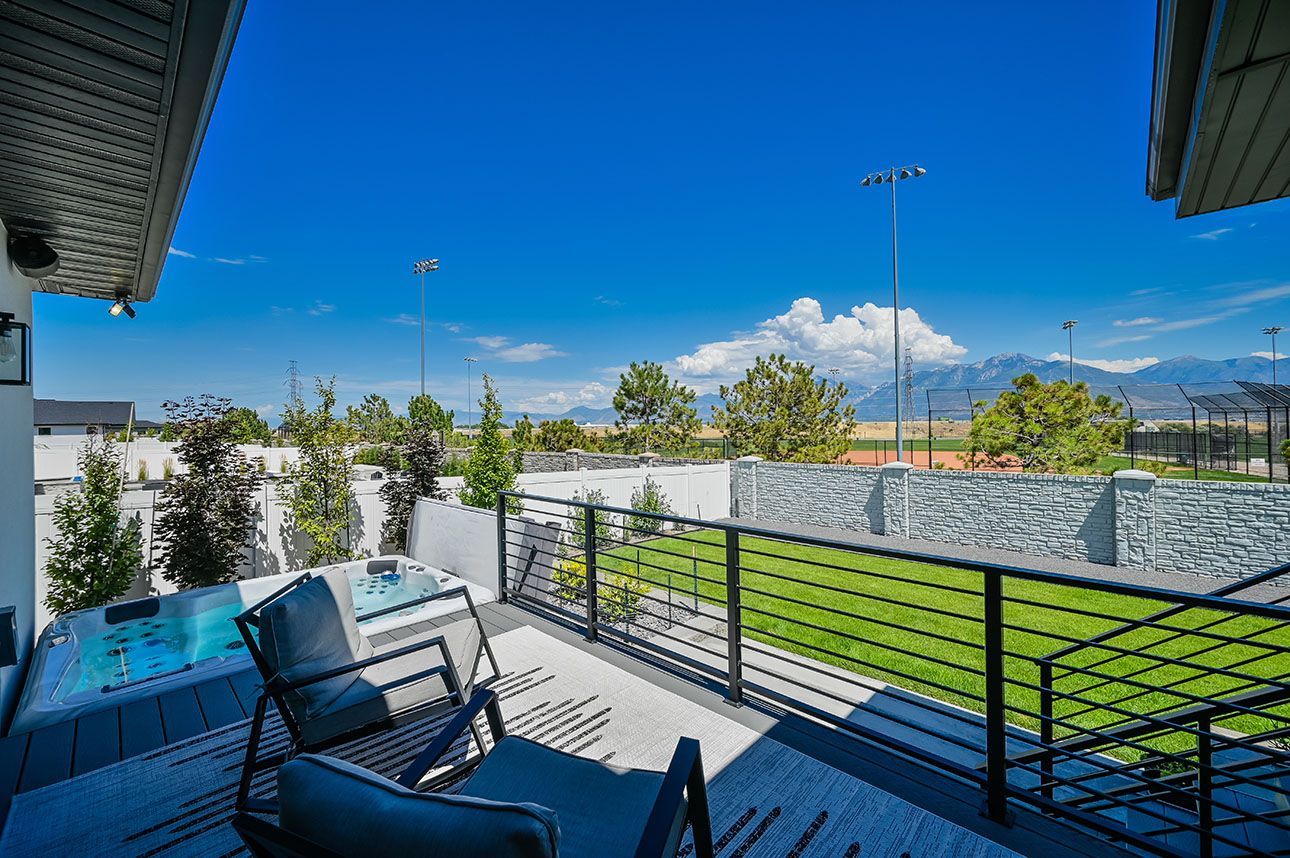A balcony with a view of a soccer field and mountains.
