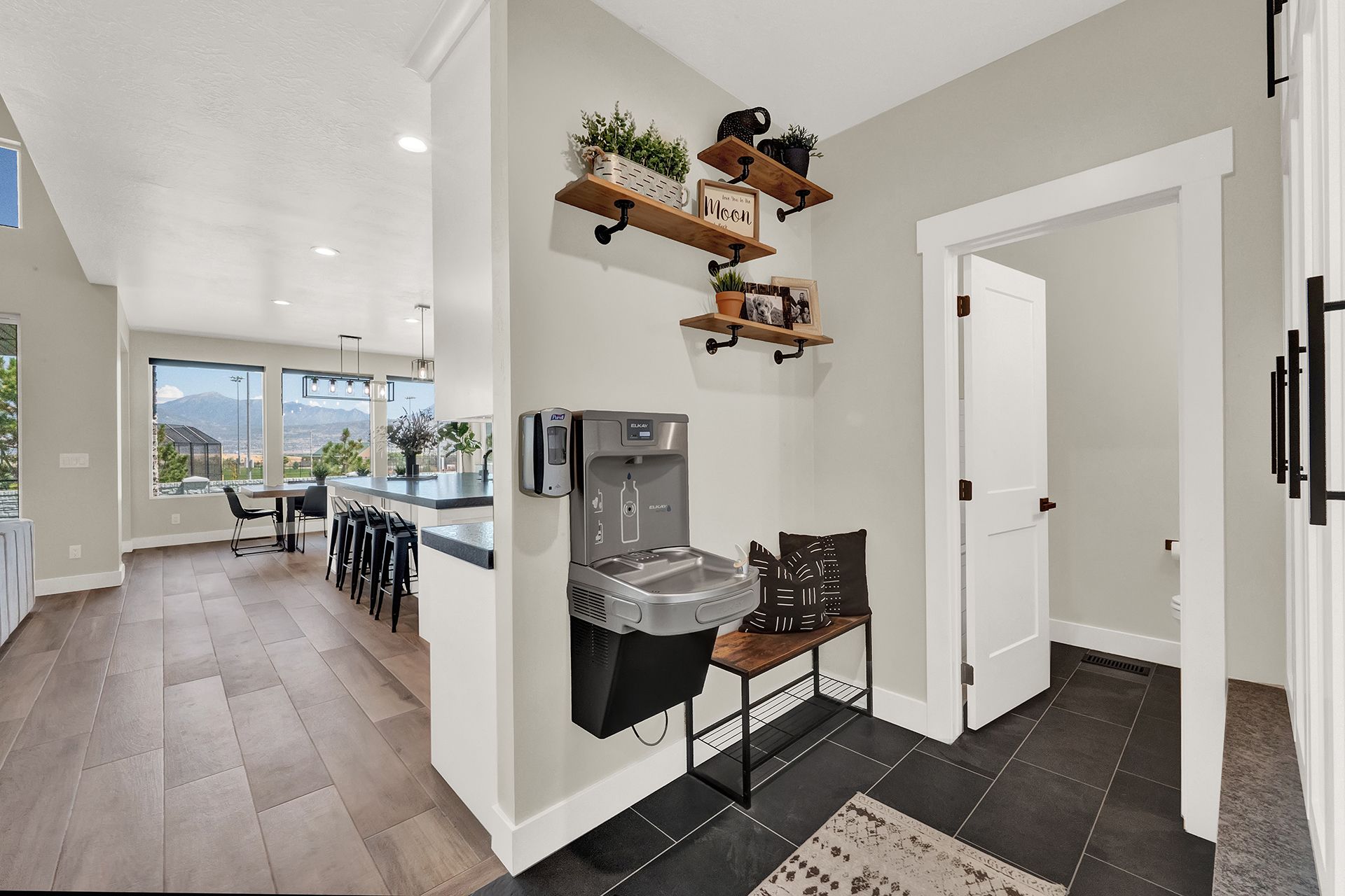 A hallway in a house with a sink and shelves.