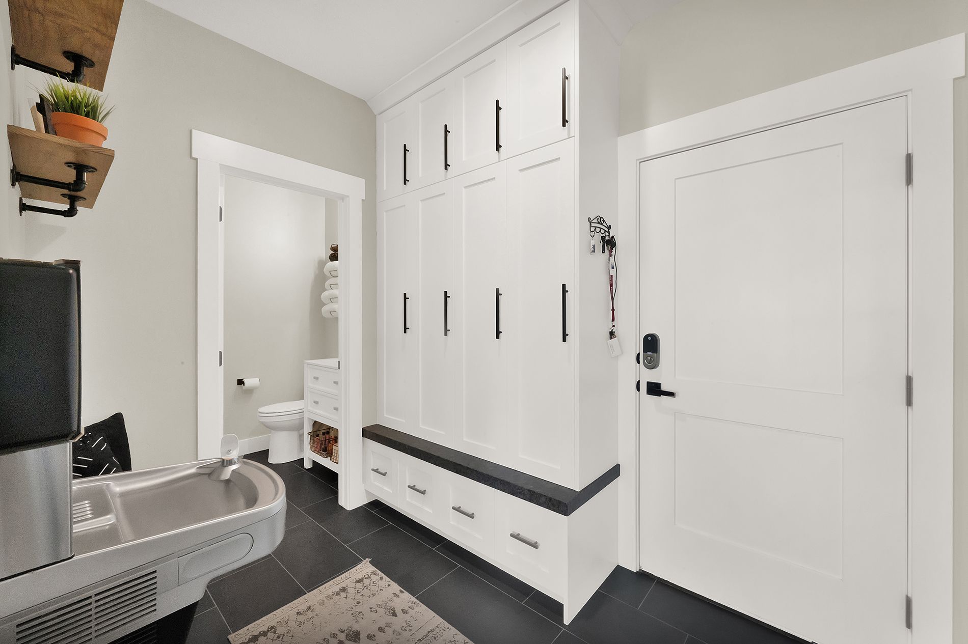 A bathroom with white cabinets , a sink , and a toilet.