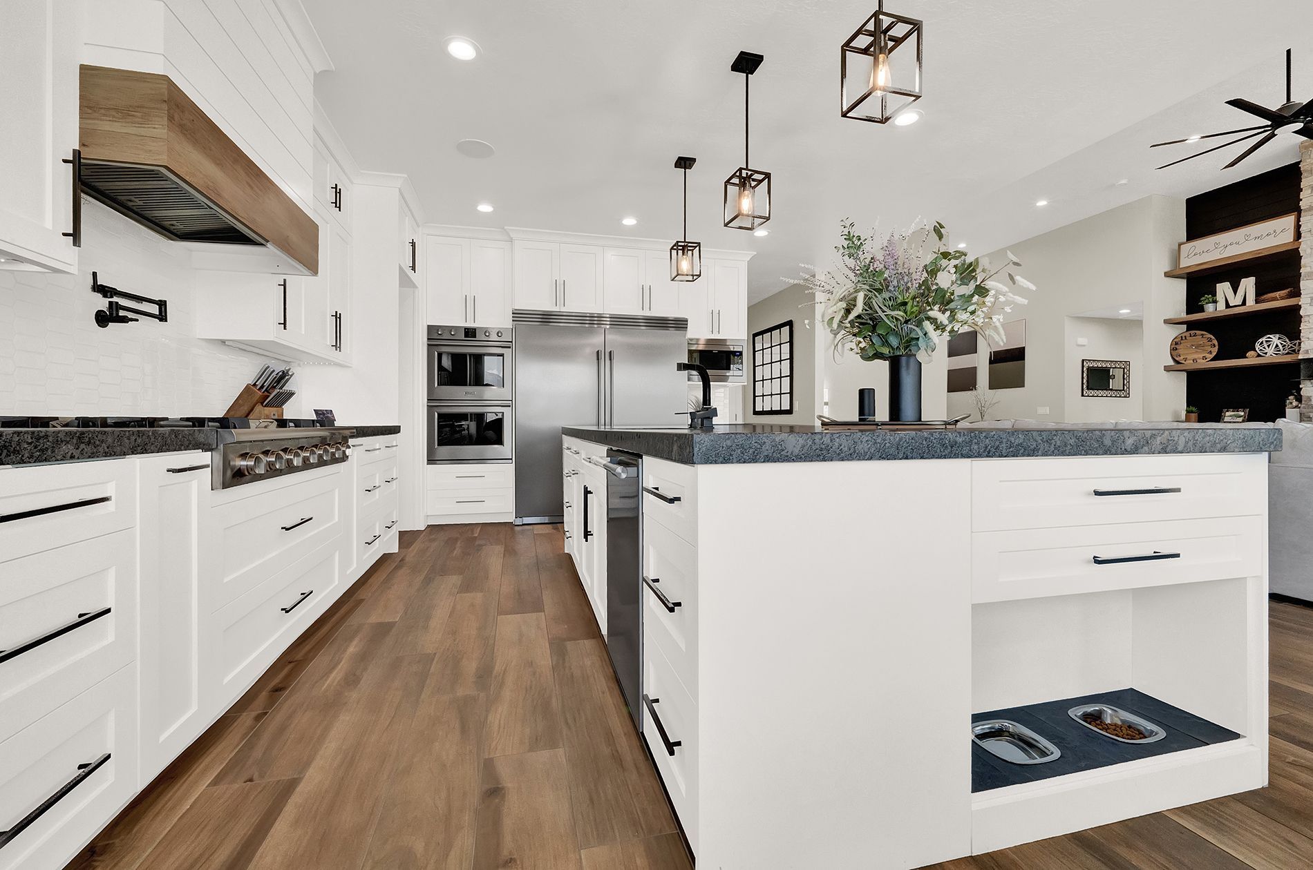 A kitchen with white cabinets and stainless steel appliances and a large island in the middle.