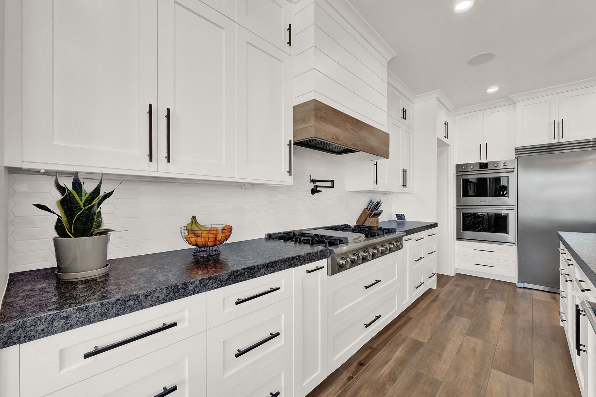 A kitchen with white cabinets , granite counter tops , and stainless steel appliances.
