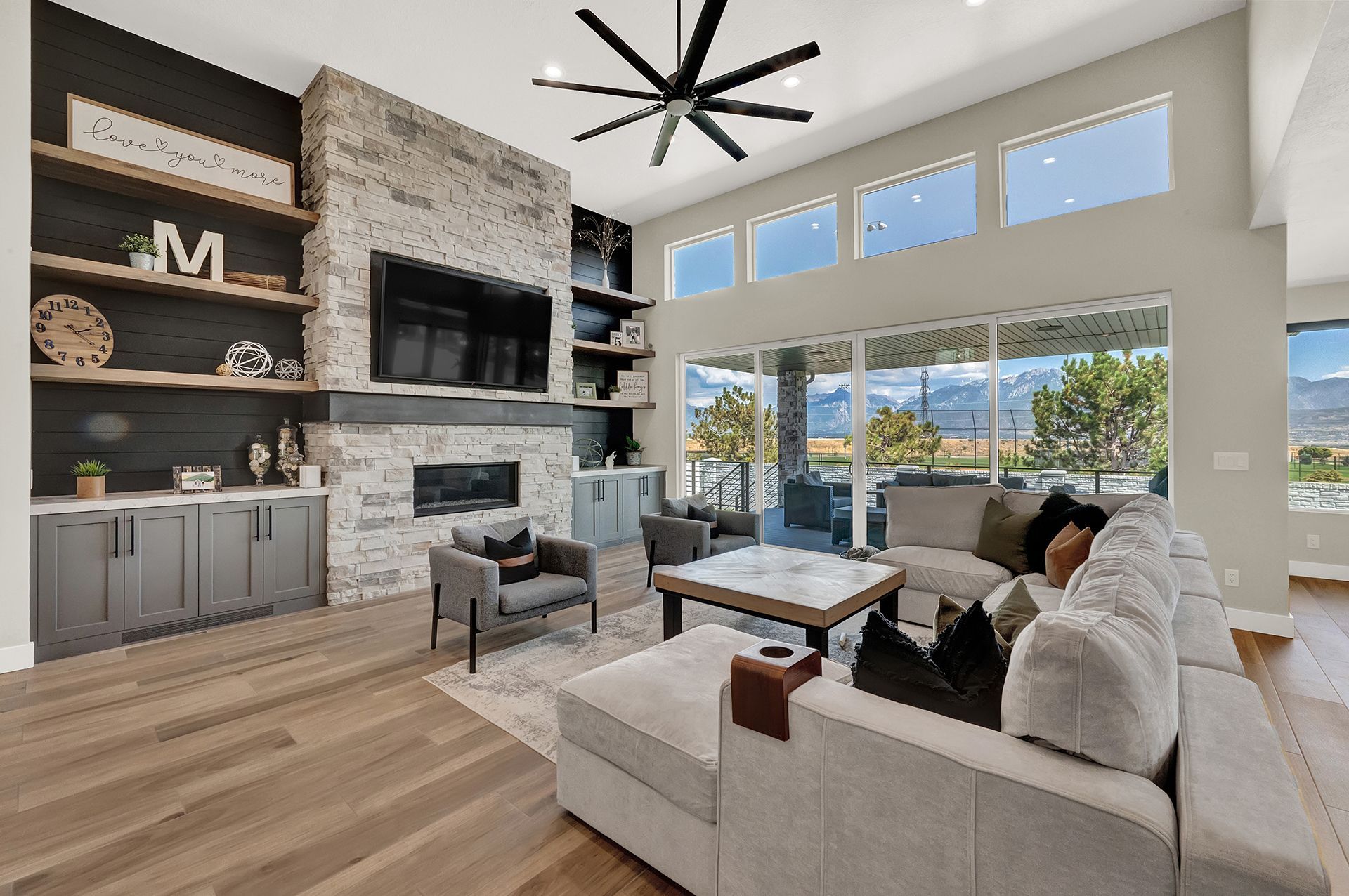 A living room with a couch , chairs , a fireplace and a ceiling fan.