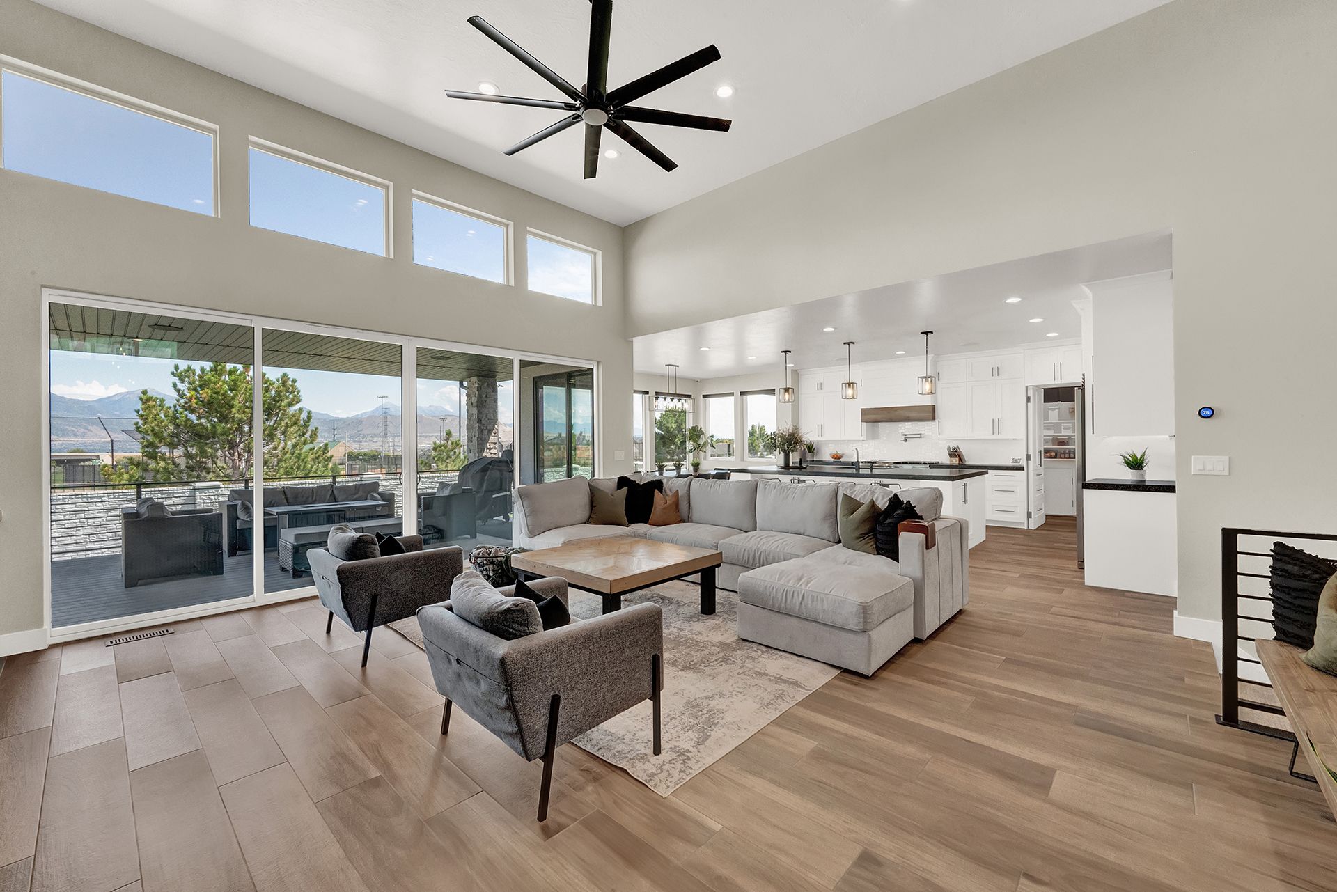 A living room with a couch , chairs , a table and a ceiling fan.