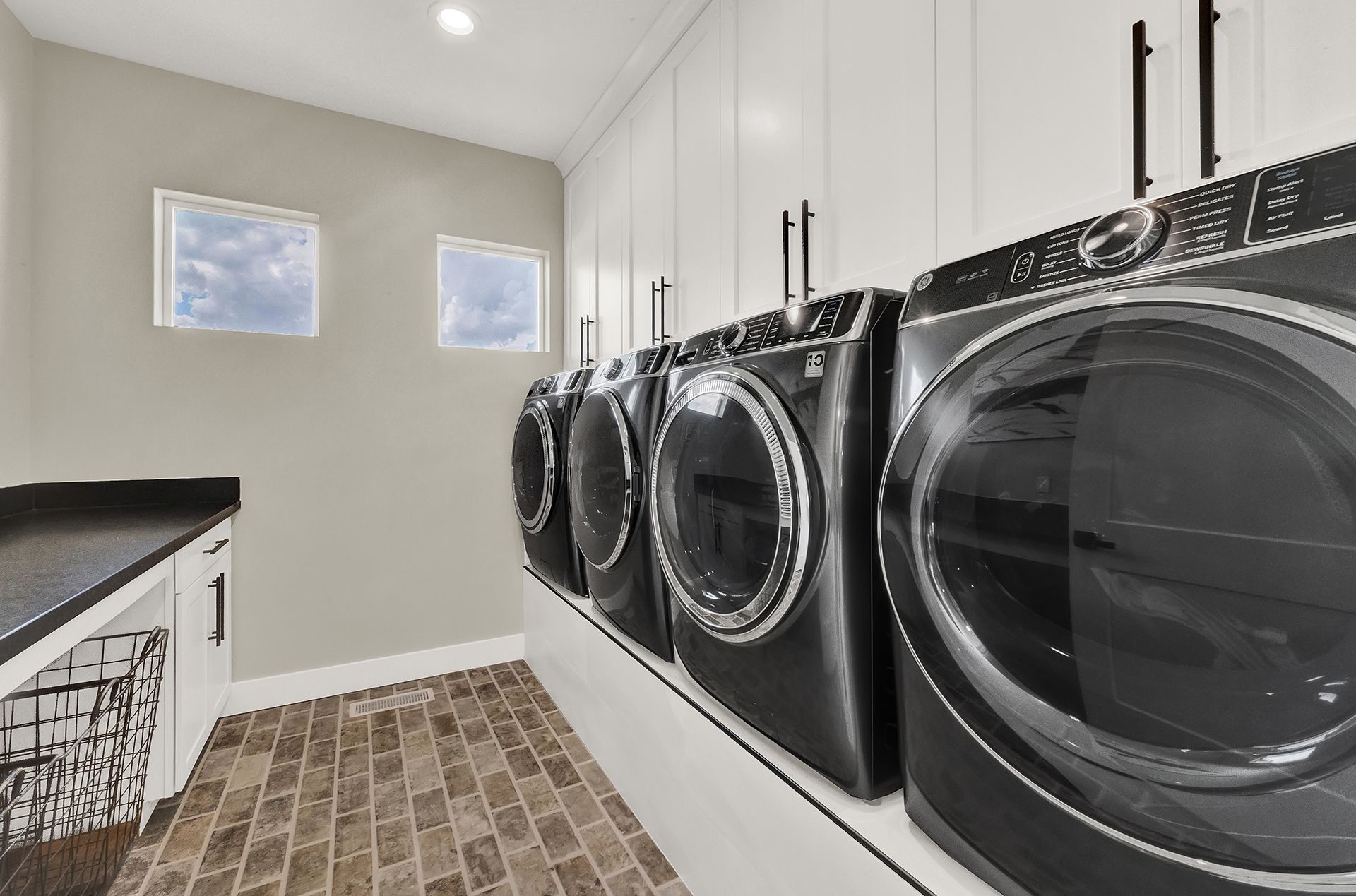 A laundry room with a row of washers and dryers.