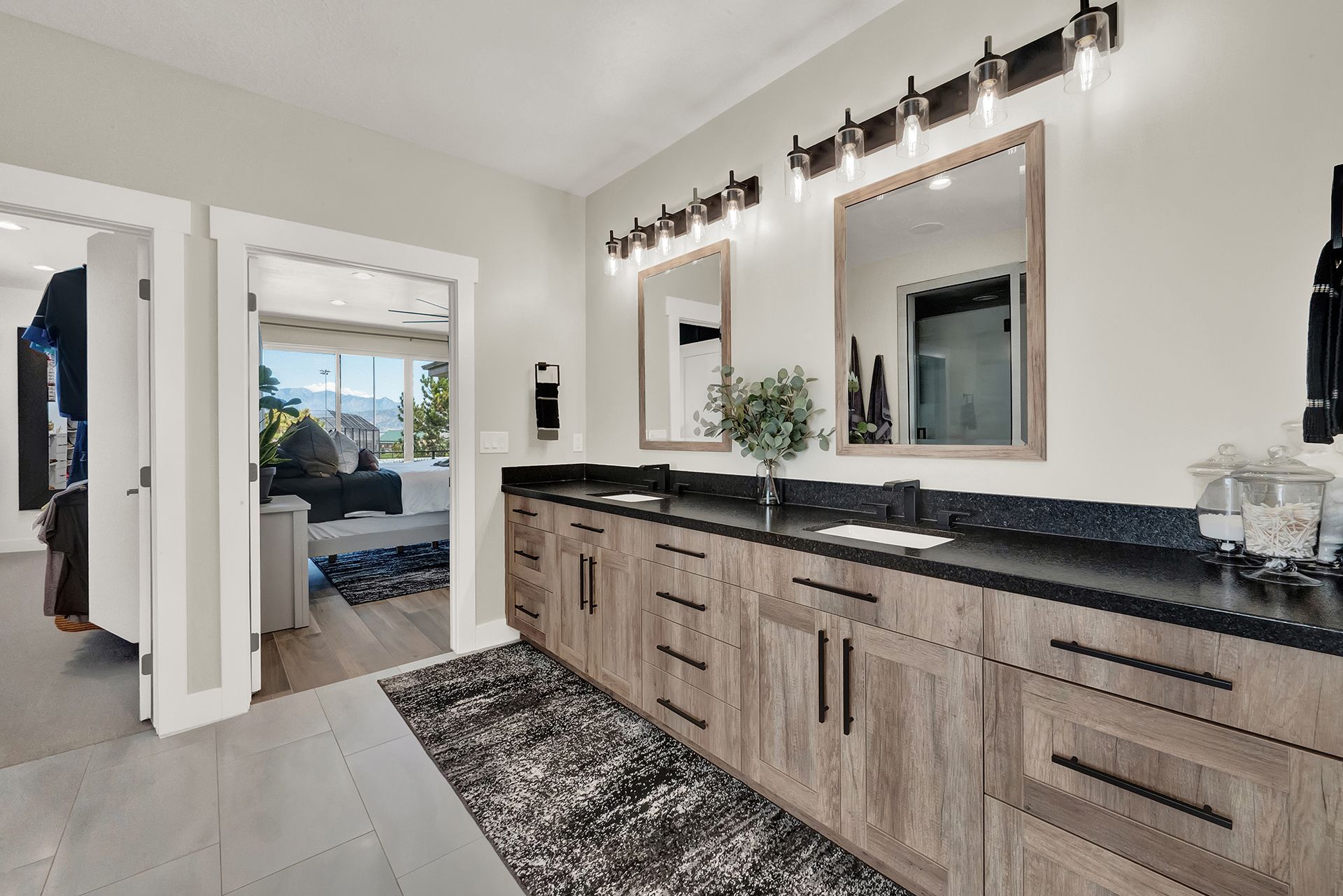 A bathroom with two sinks , two mirrors and a rug.