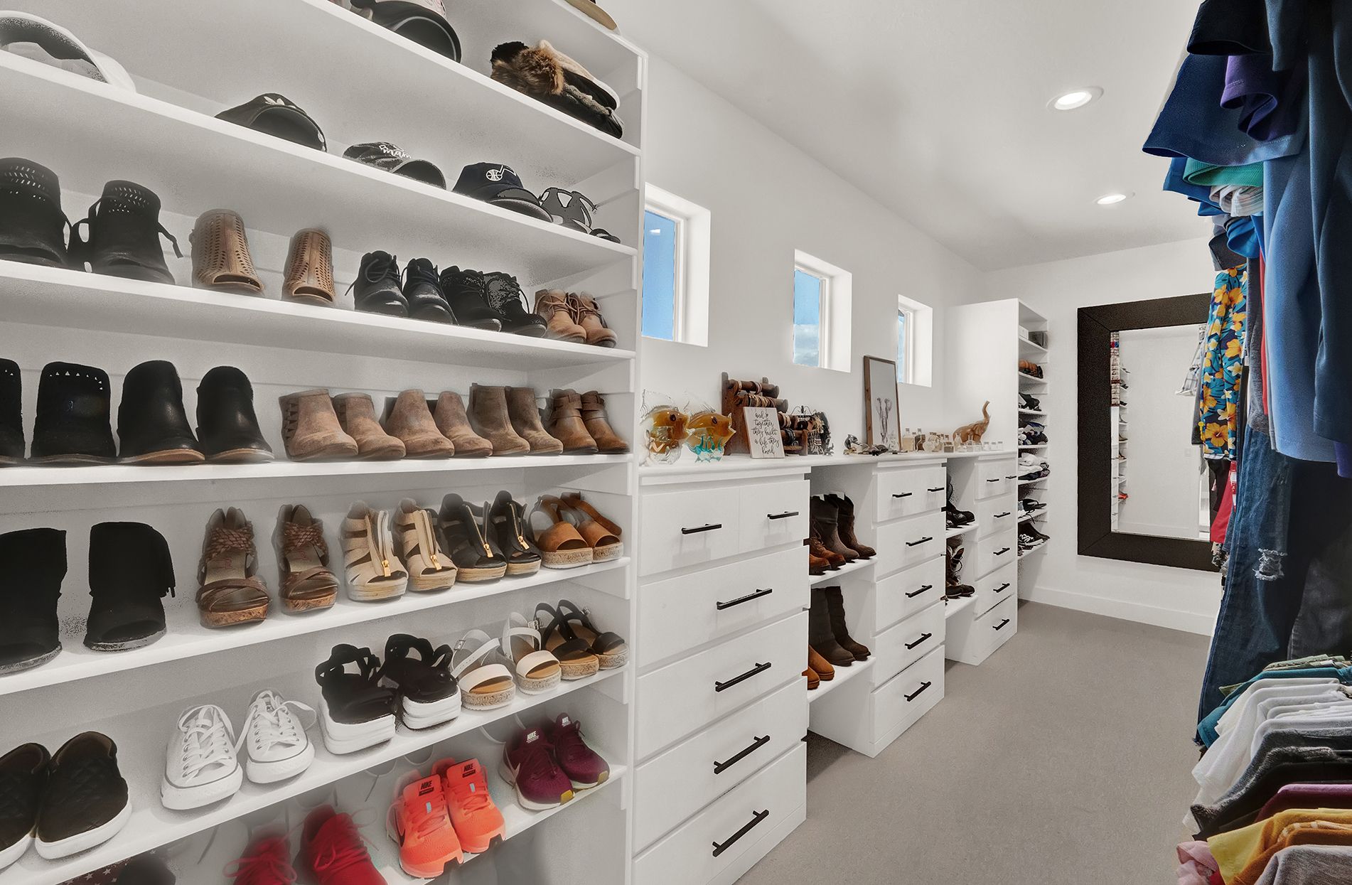 A walk in closet filled with lots of shoes and clothes.