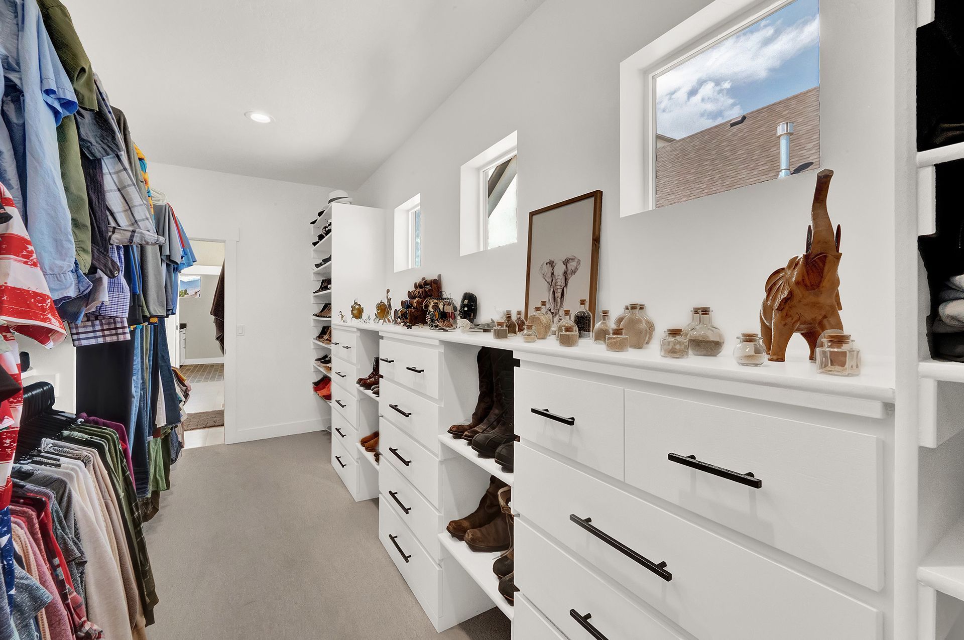 A walk in closet filled with lots of clothes and dressers.