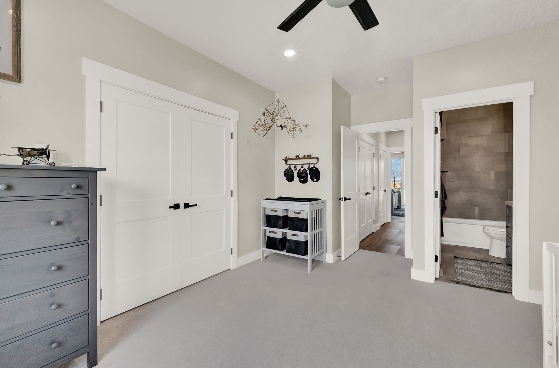 A bedroom with a dresser and a ceiling fan.