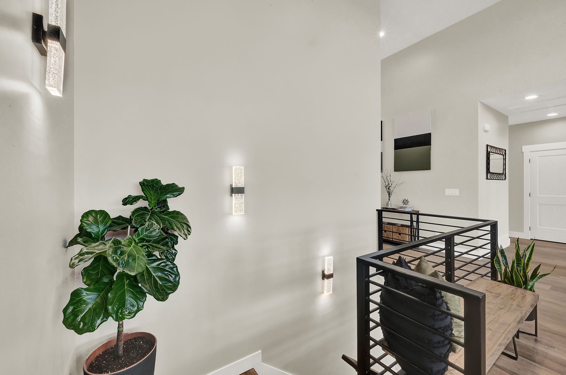 A potted plant is sitting in a hallway next to a staircase.