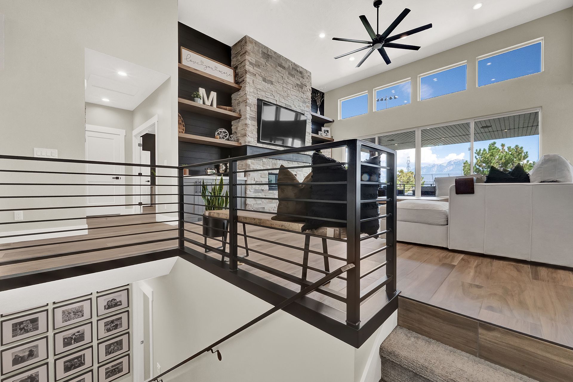 A living room with a balcony and a ceiling fan