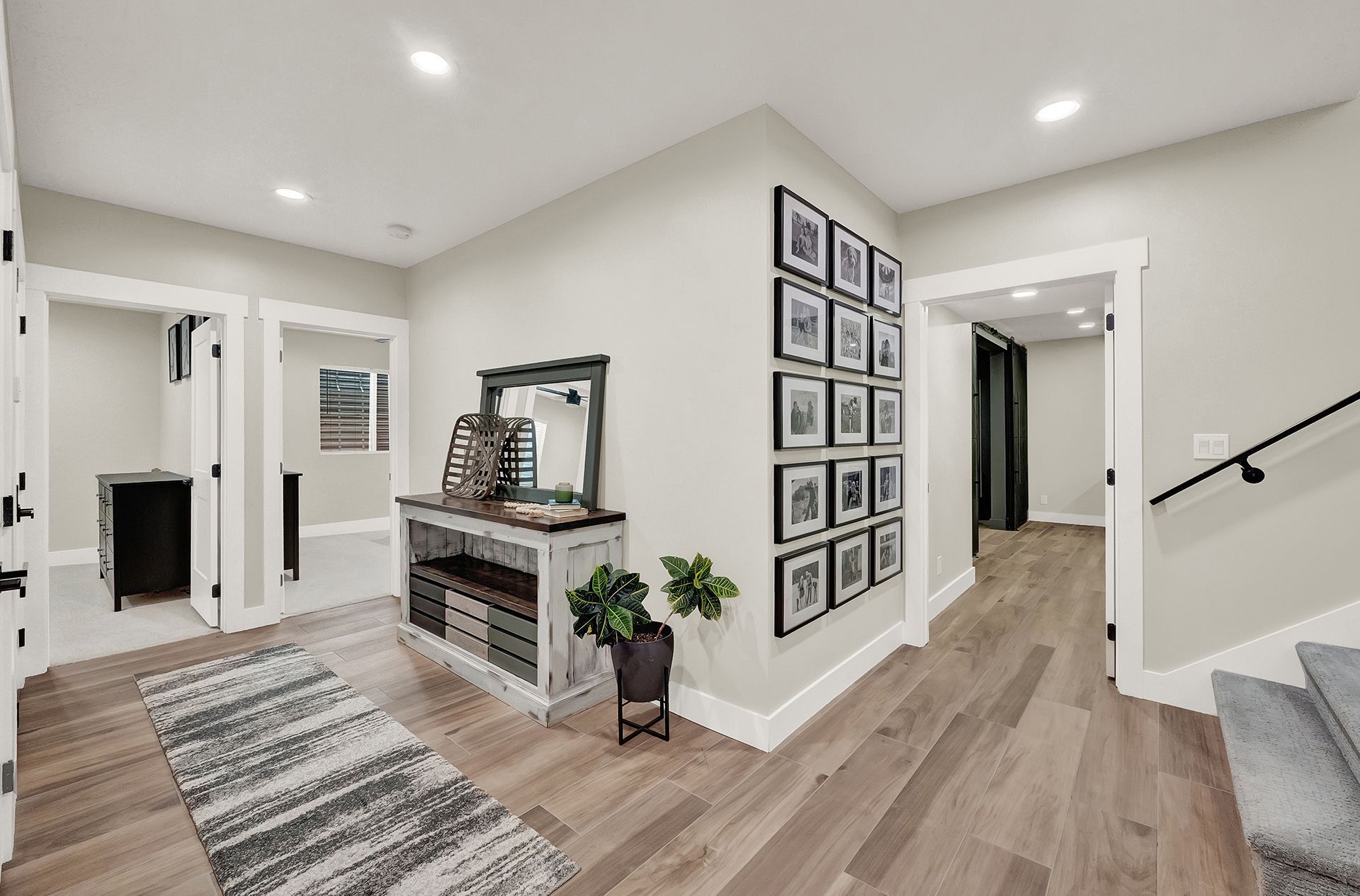 A hallway with hardwood floors , a table , a mirror and pictures on the wall.