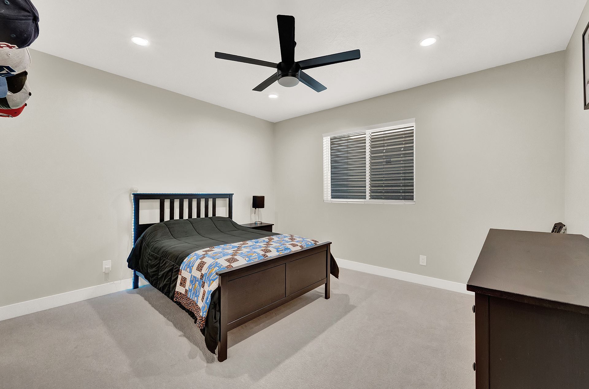 A bedroom with a bed , dresser , and ceiling fan.