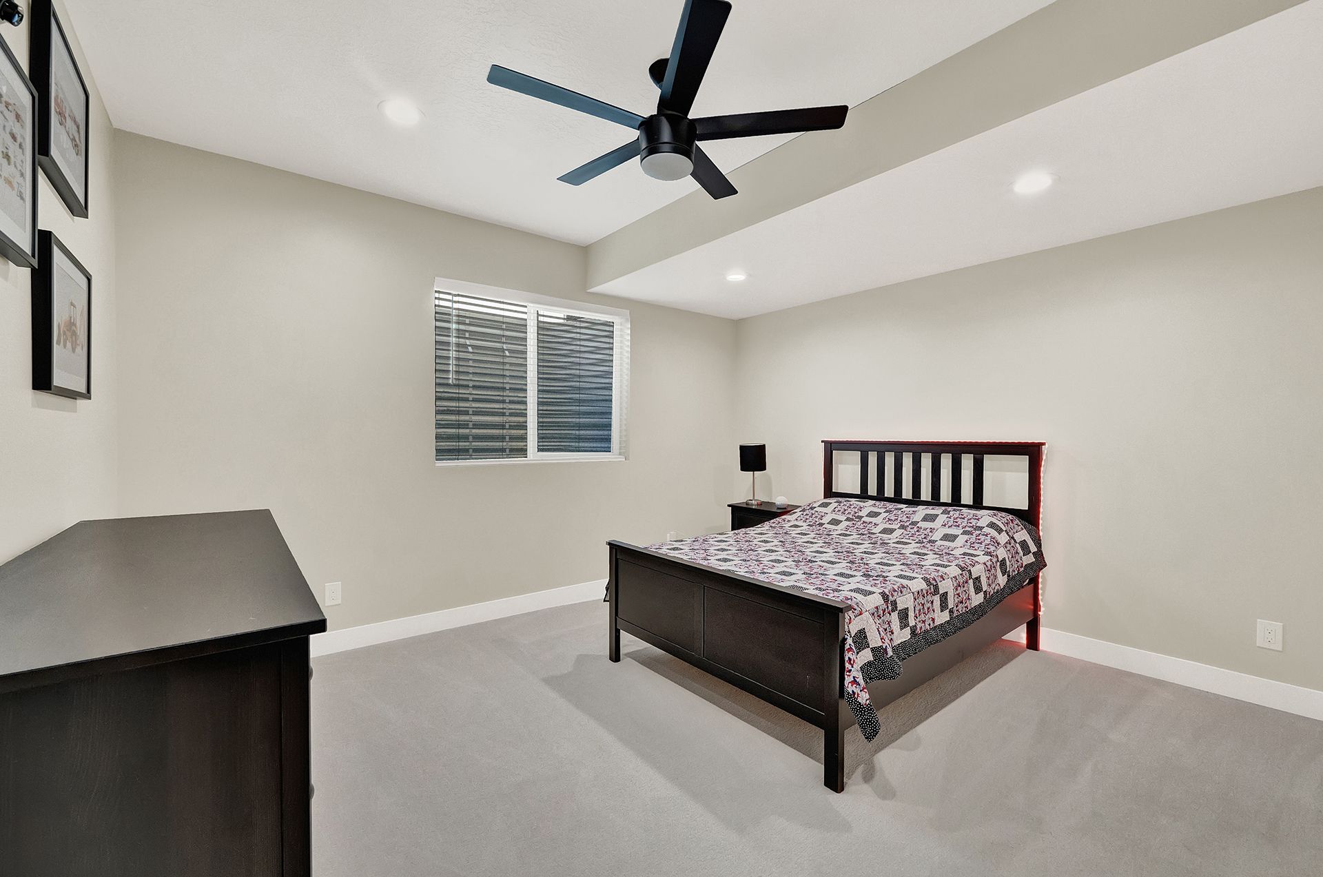 A bedroom with a bed , dresser , and ceiling fan.