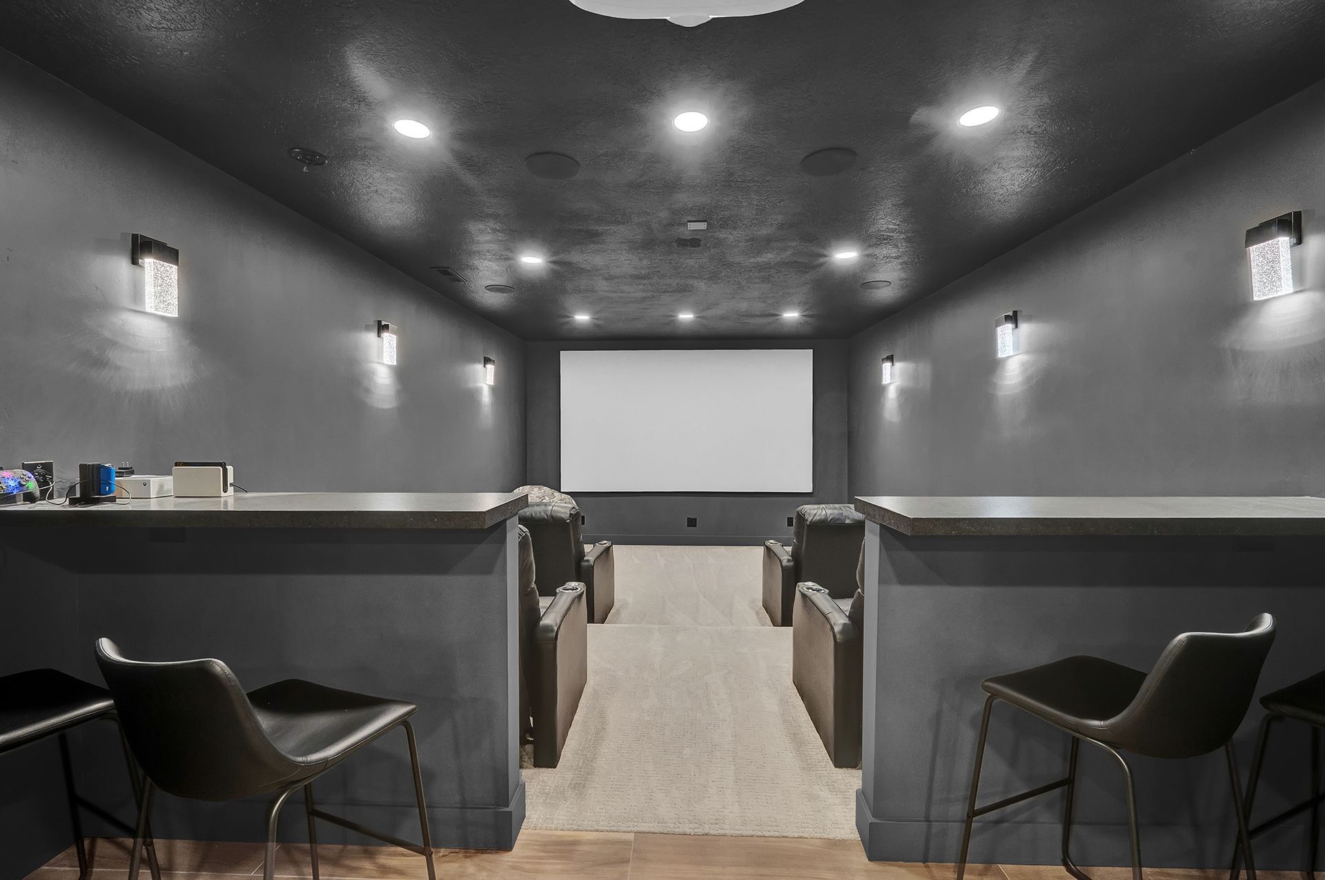 A home theater with a bar and chairs and a large screen.