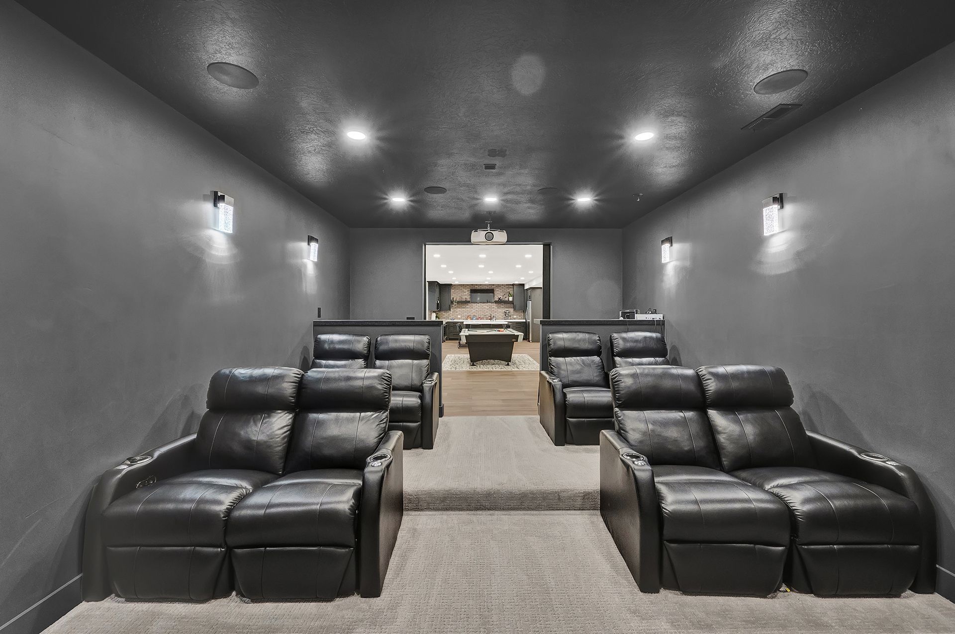 A home theater with black leather seats and a projector screen.