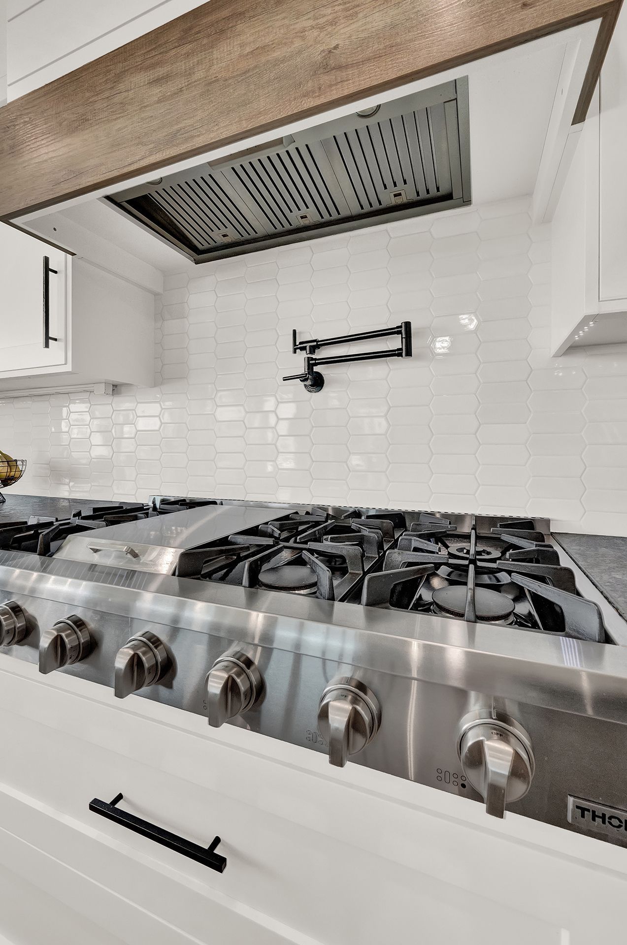 A stainless steel stove top oven in a kitchen with white cabinets.