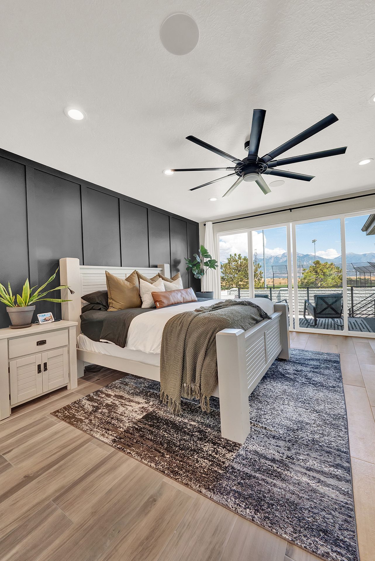 A bedroom with a bed , nightstand , rug and ceiling fan.