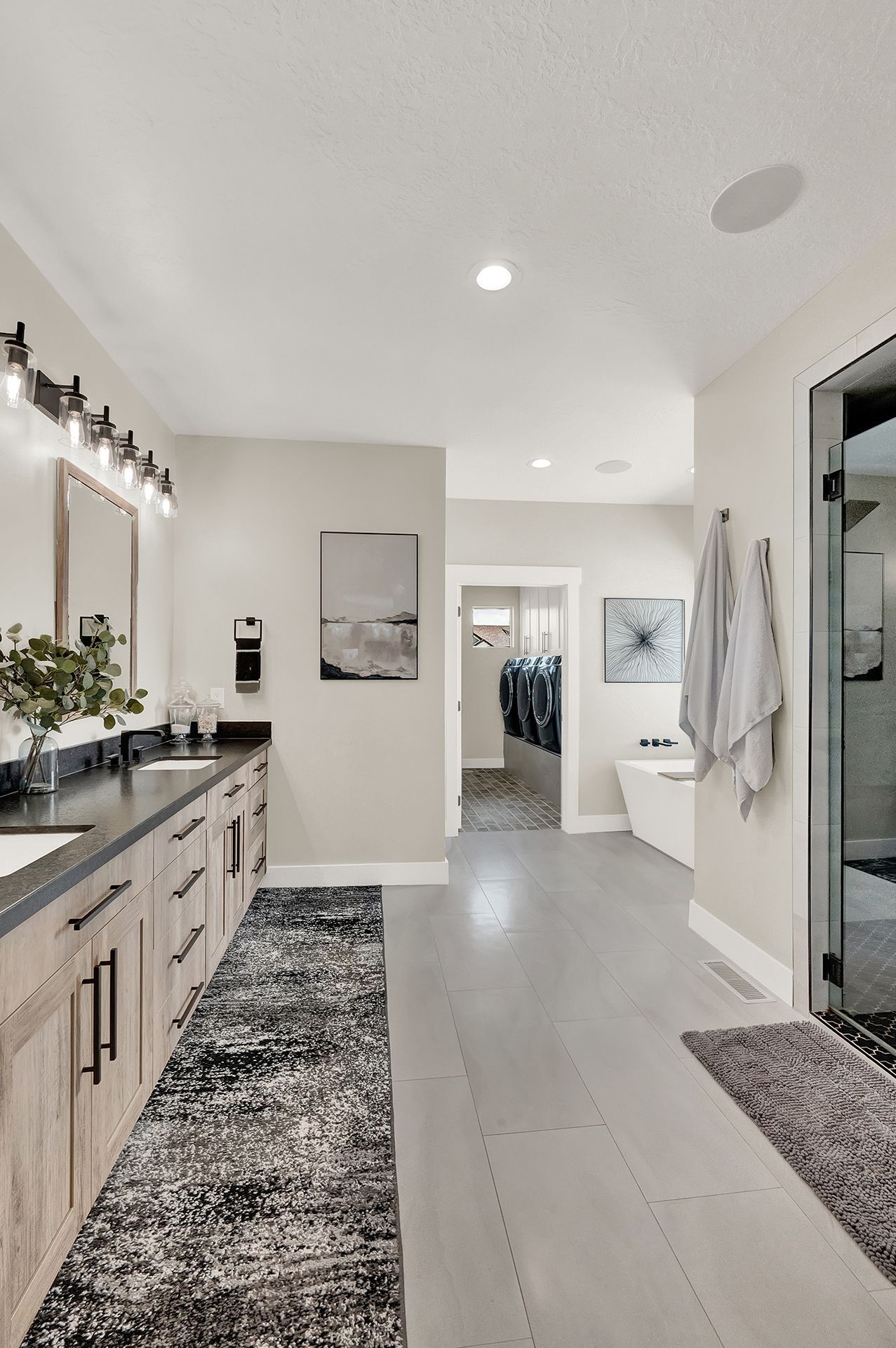 A bathroom with two sinks , a tub , a mirror and a rug.
