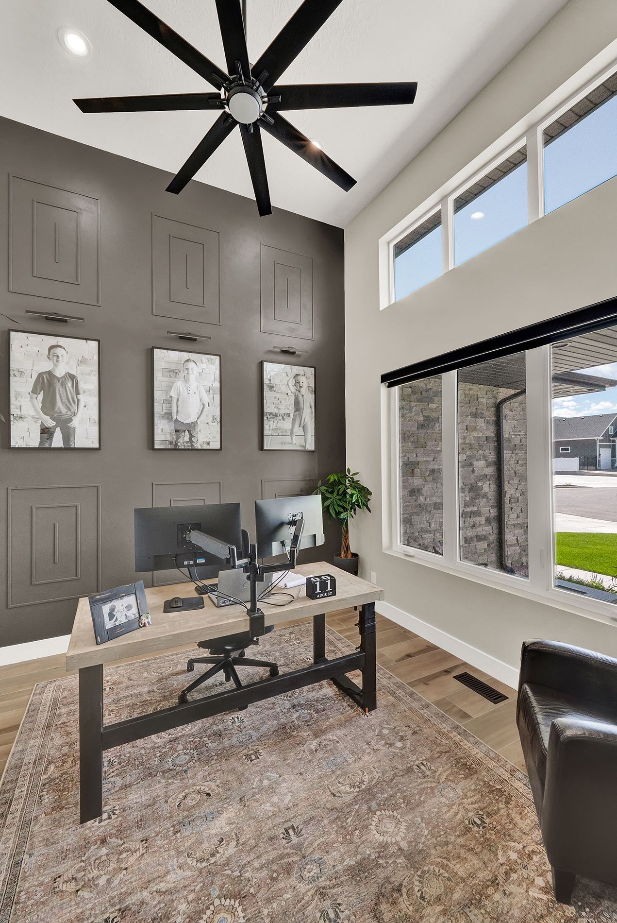 A home office with a desk , chair , computer and ceiling fan.