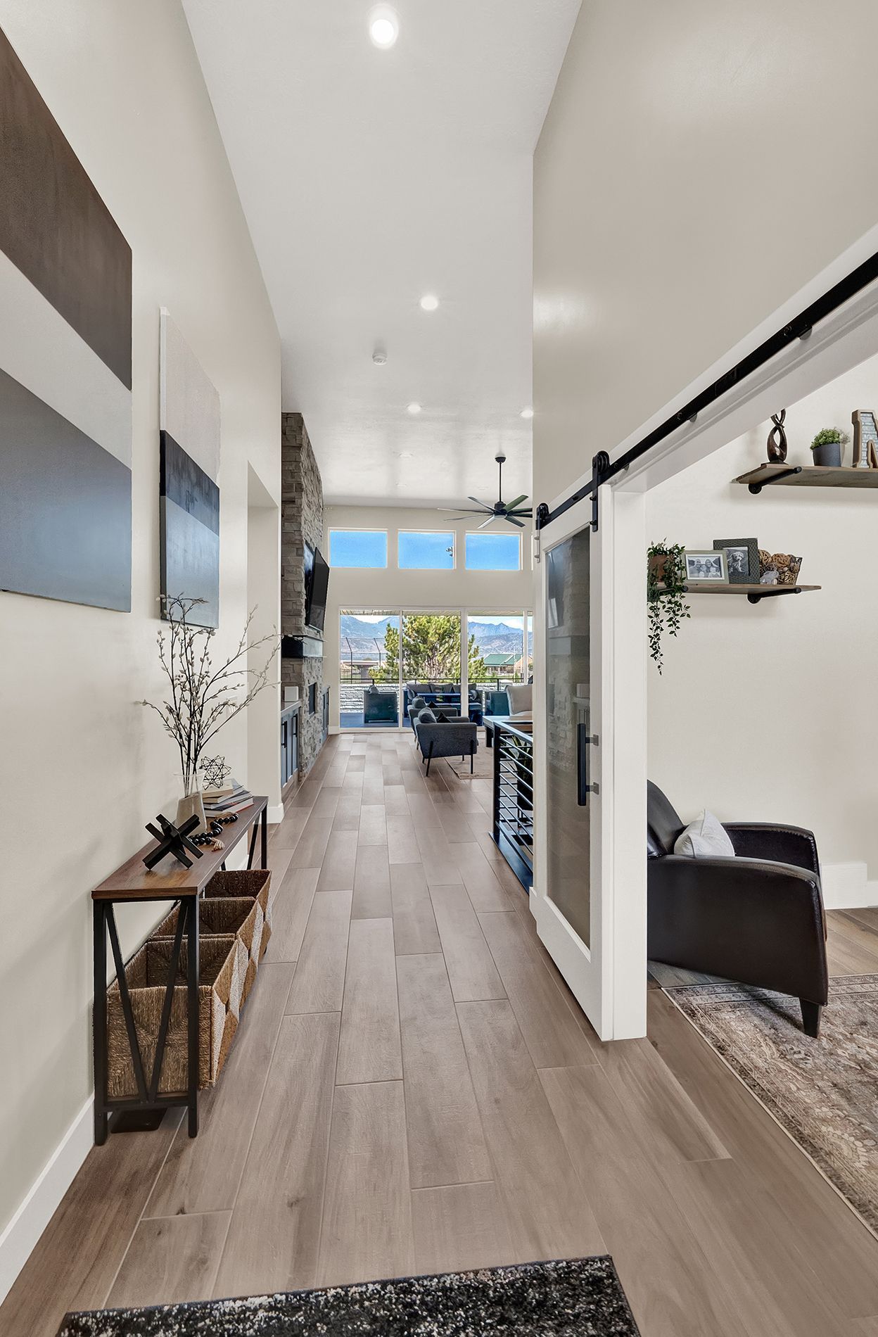 A hallway in a house with hardwood floors and a sliding barn door leading to a living room.
