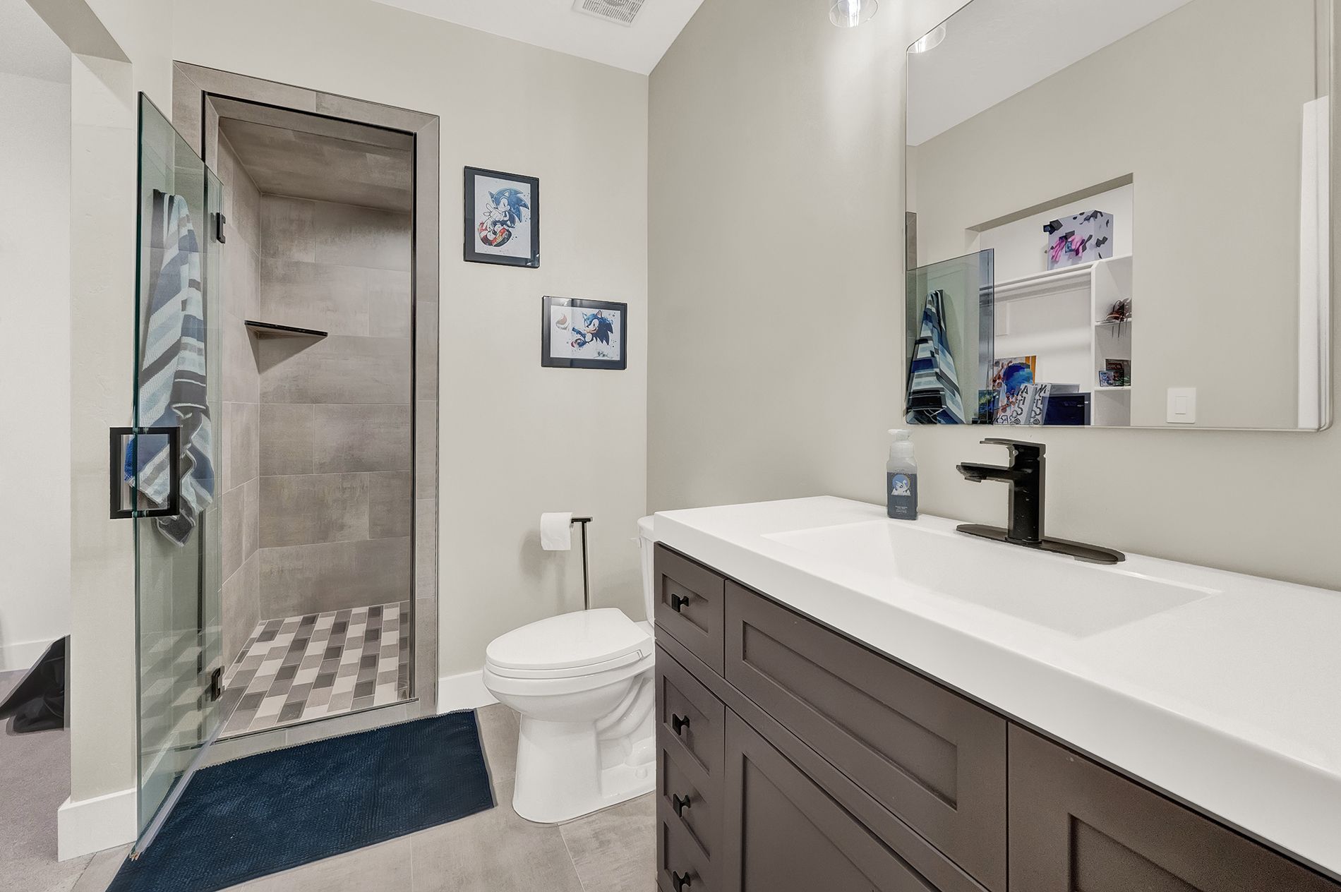 A bathroom with a toilet , sink , mirror and walk in shower.