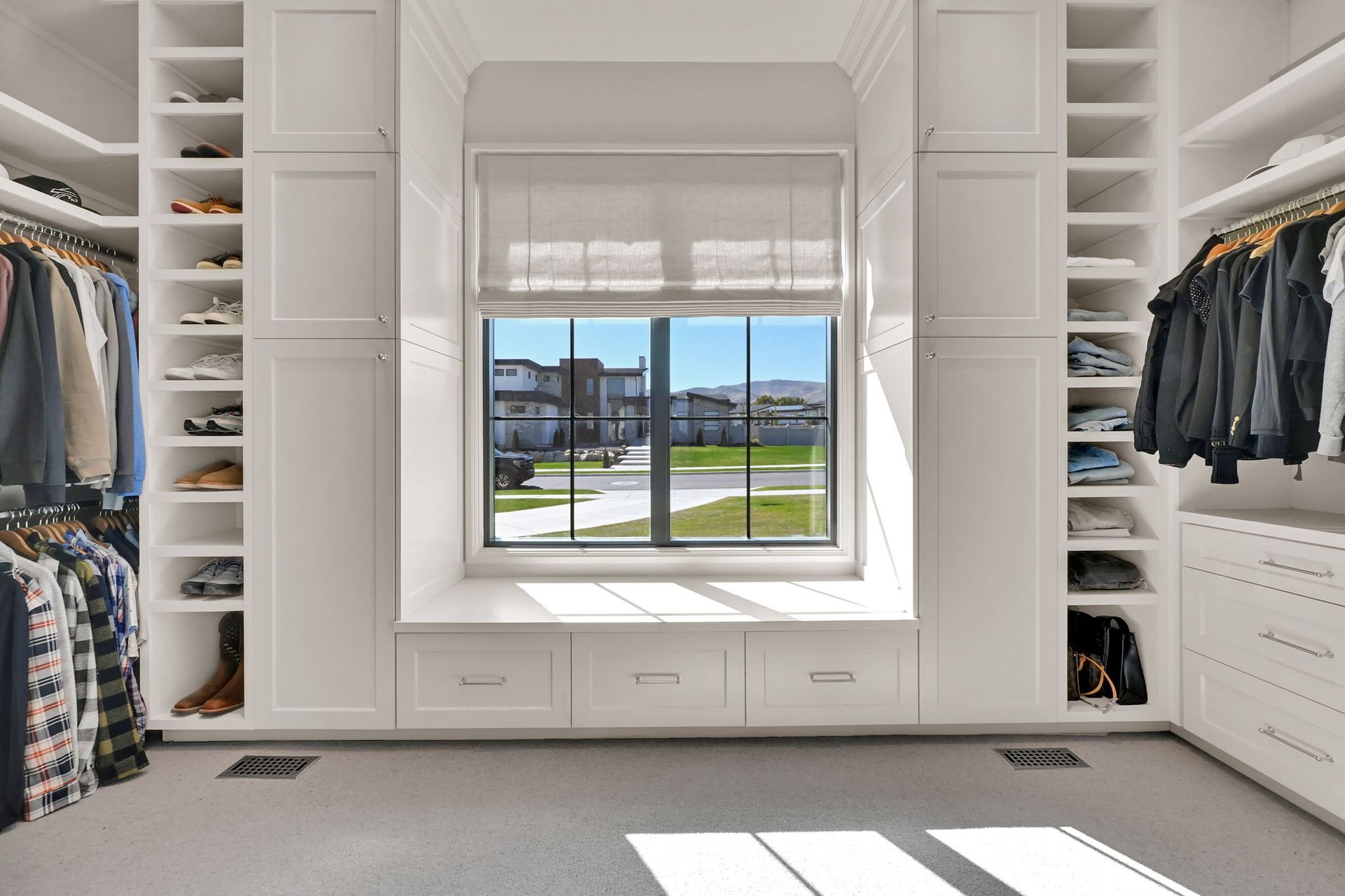 A walk in closet with lots of clothes and a window