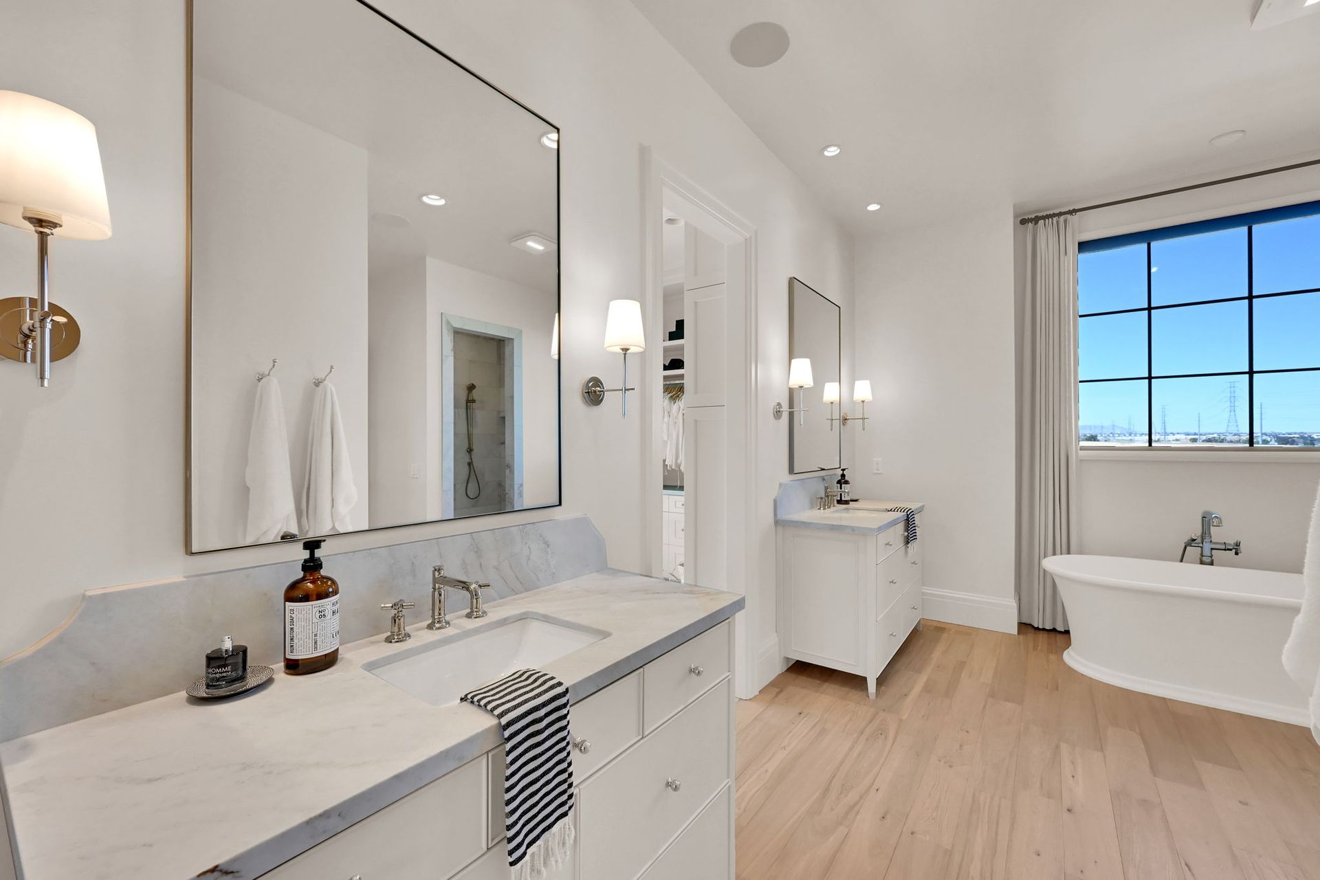 A bathroom with two sinks , two mirrors and a tub.