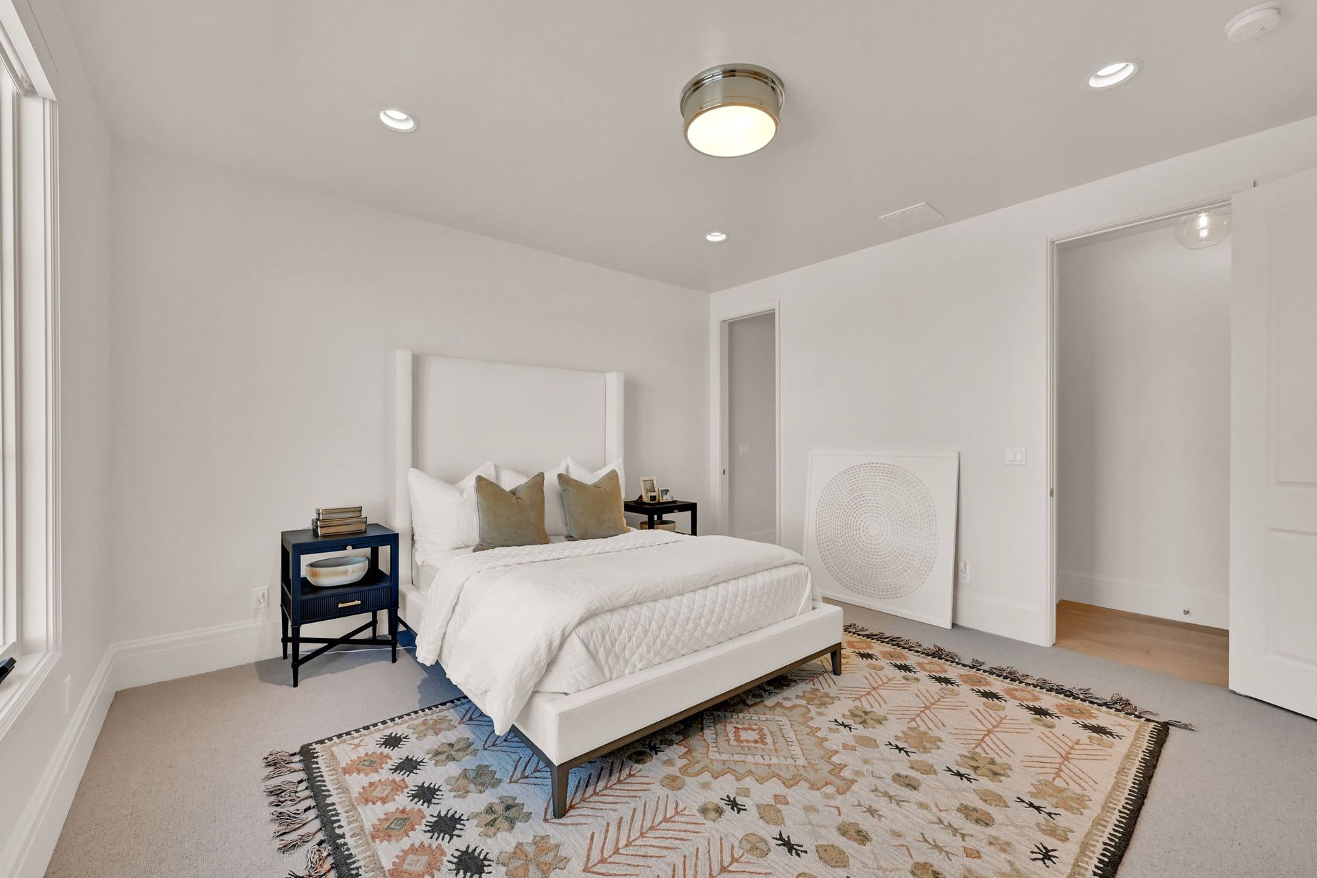 A bedroom with a bed , nightstands , and a rug.
