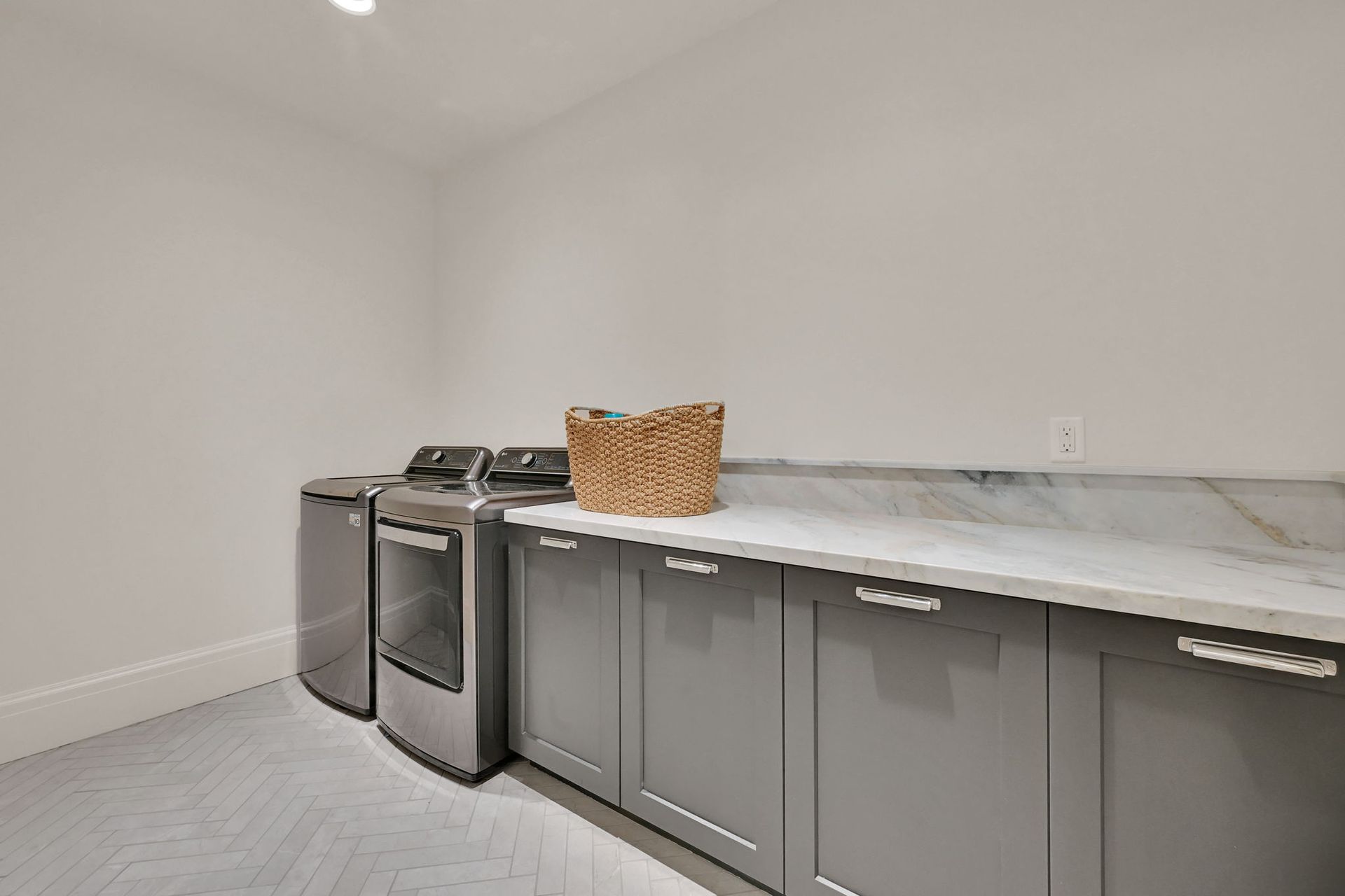 A laundry room with a washer and dryer and a basket on the counter.