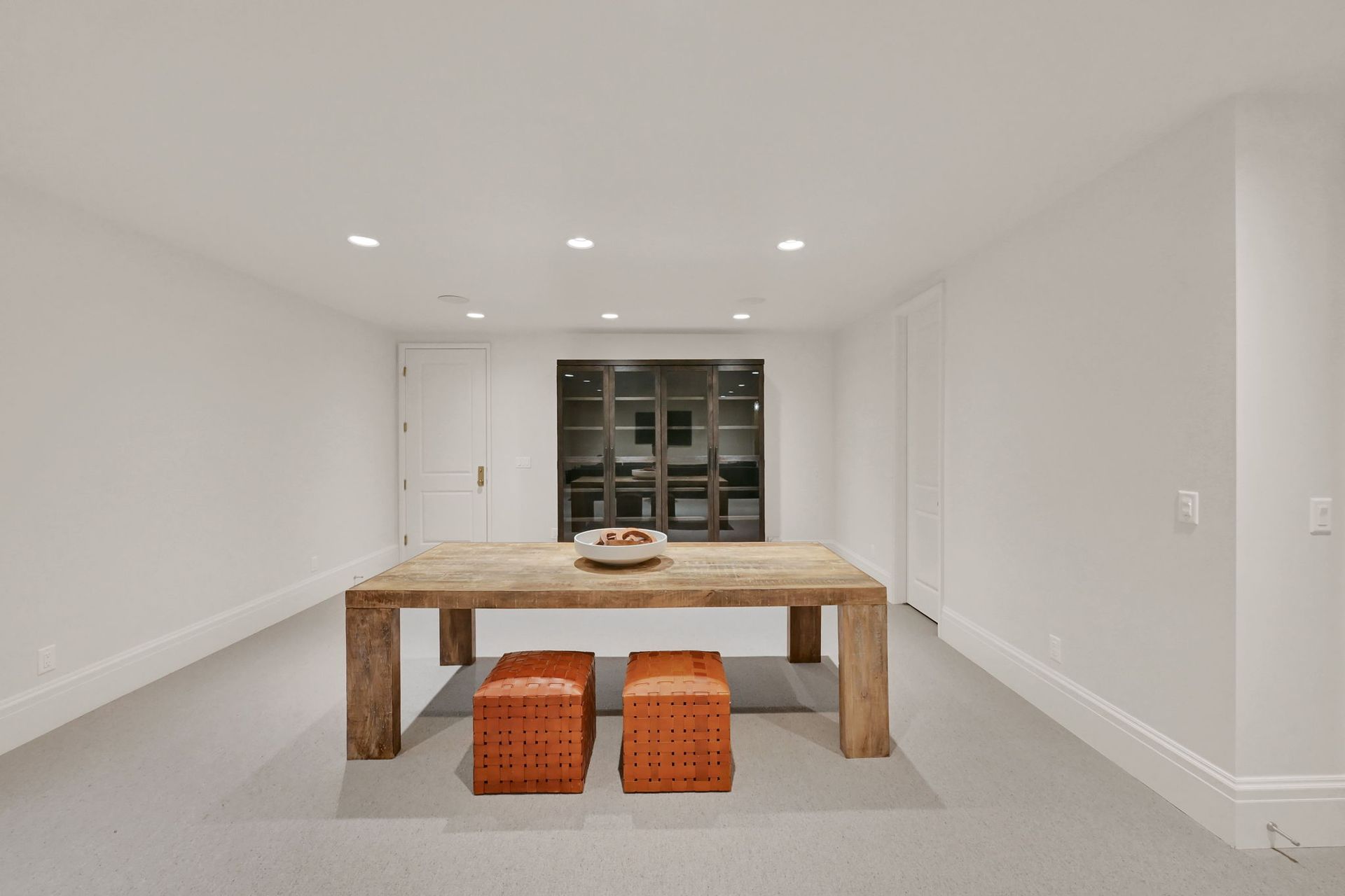A dining room with a wooden table and two ottomans.