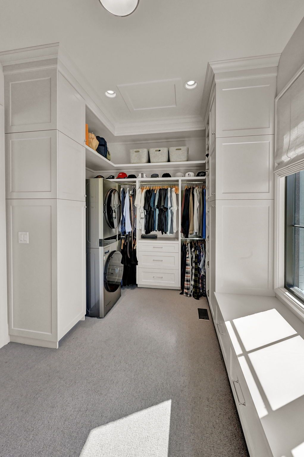 A walk in closet with a washer and dryer and a window.