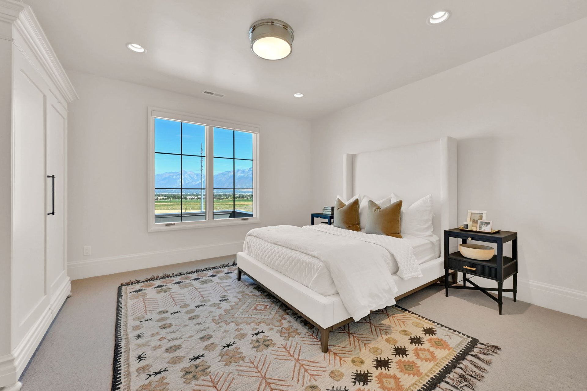A bedroom with a bed , nightstand , rug and window.