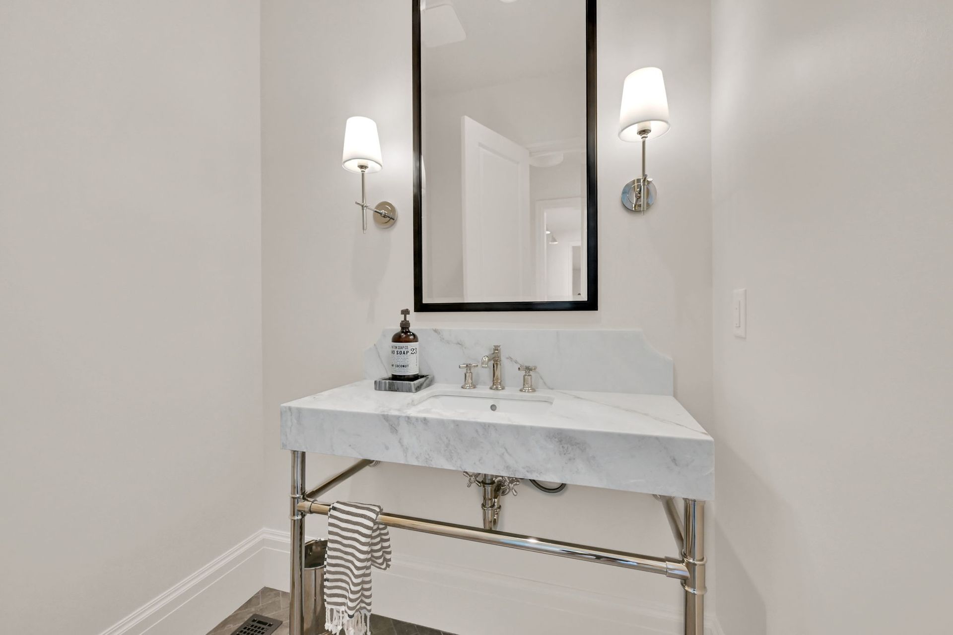 A bathroom with a sink , mirror and lights.
