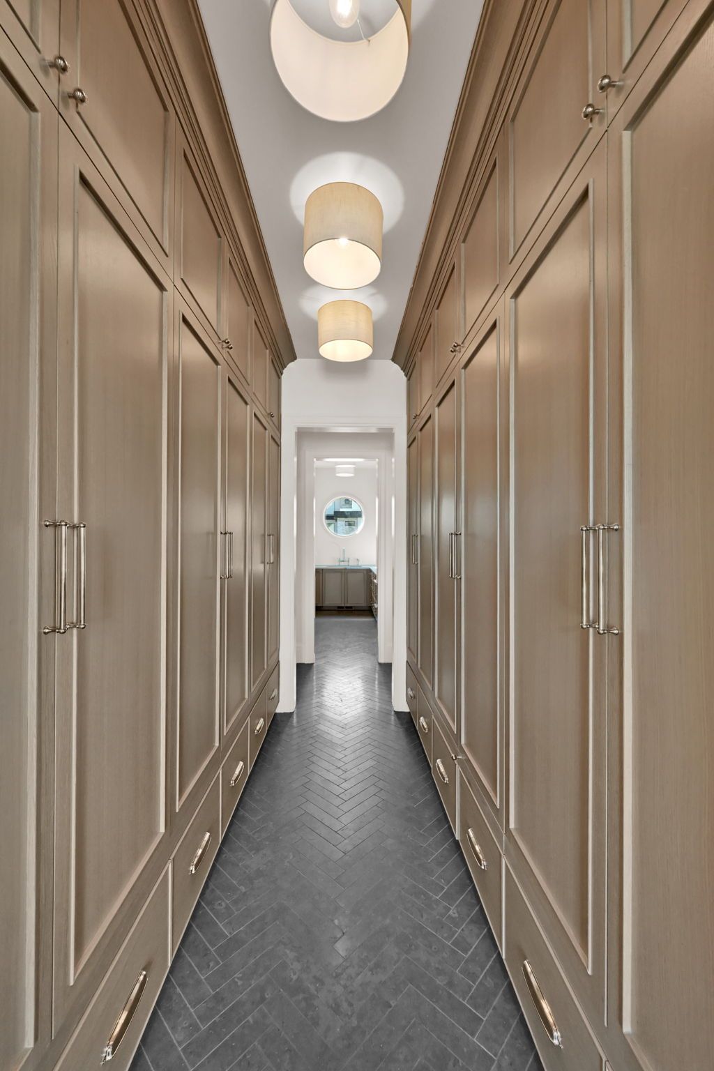 A long hallway with lots of cabinets and drawers and a ceiling light.