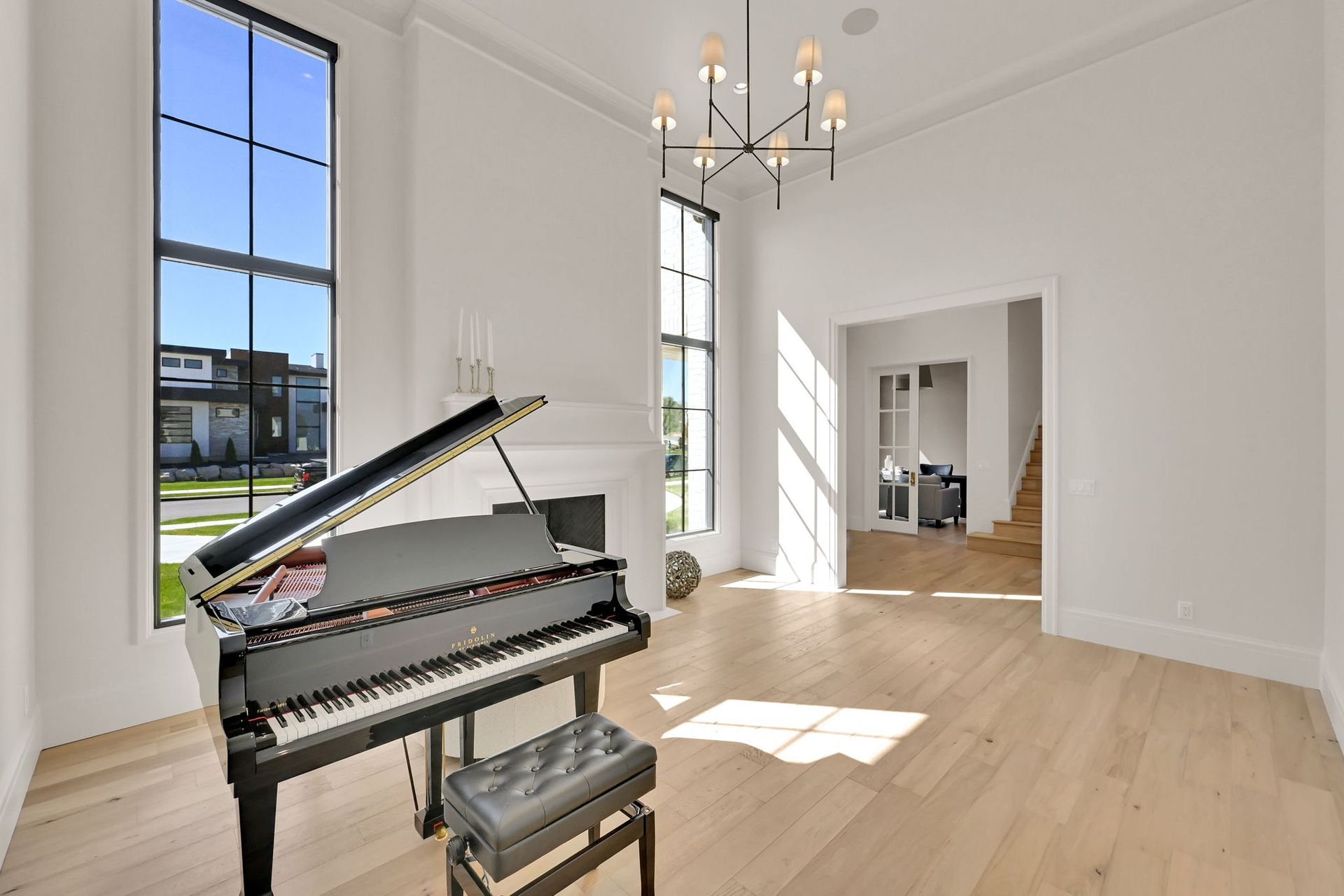 An empty living room with a piano and a chandelier