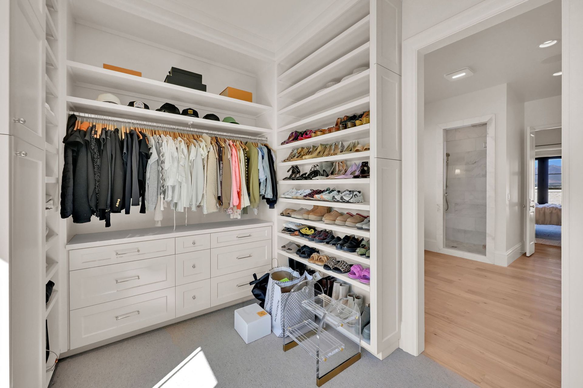 A walk in closet filled with lots of clothes and shoes.